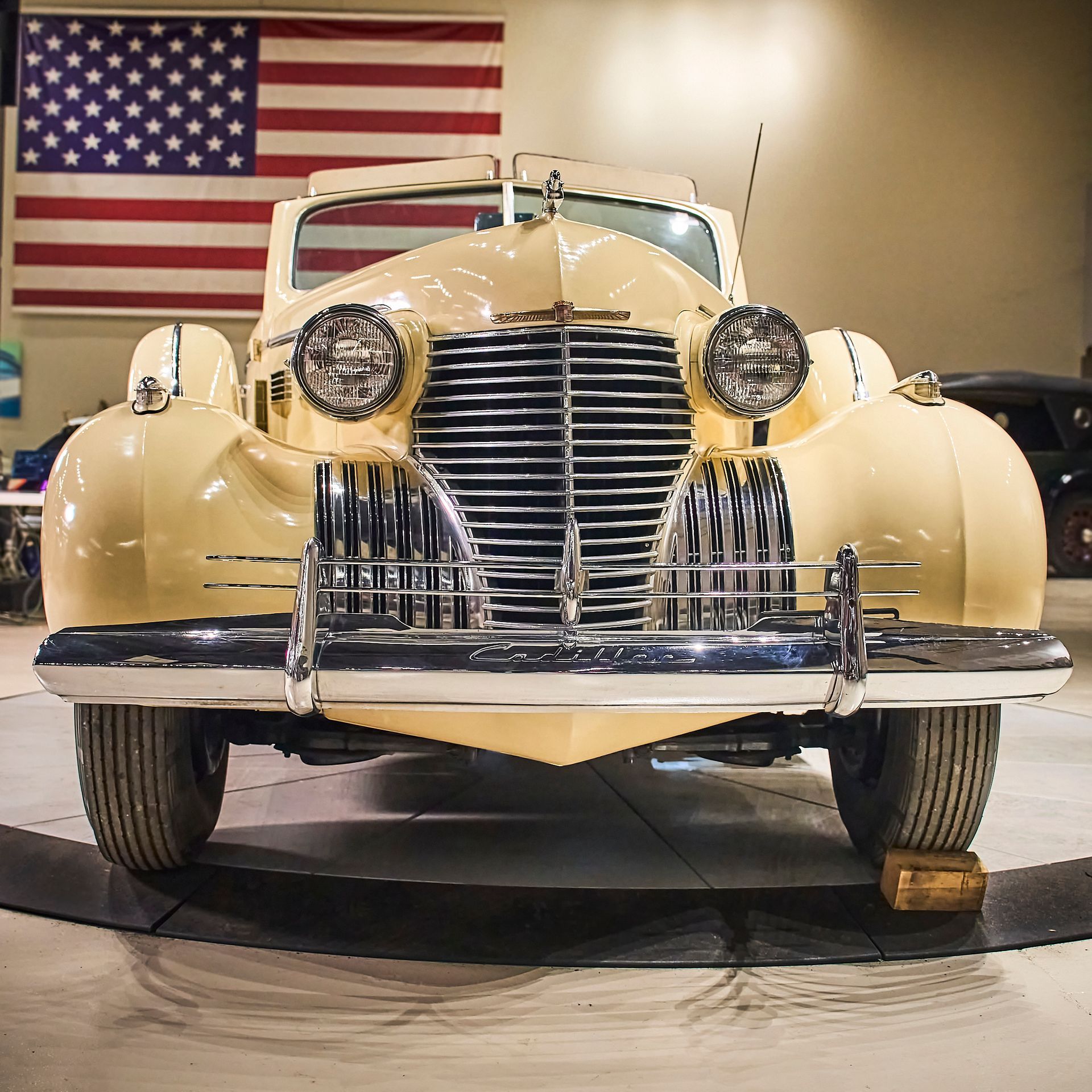 An old car is parked in front of an american flag