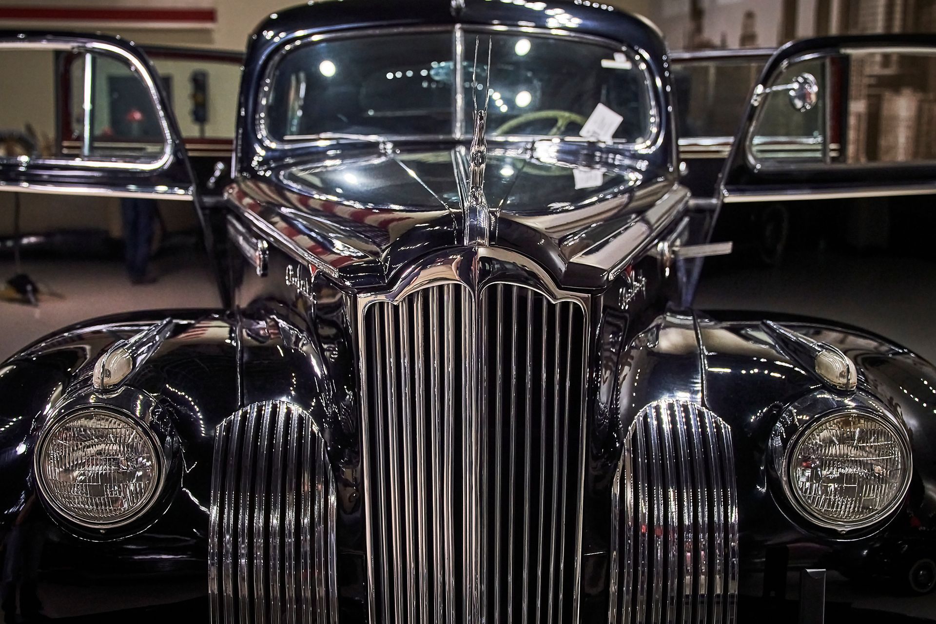 A black car with a chrome grill is parked in a garage