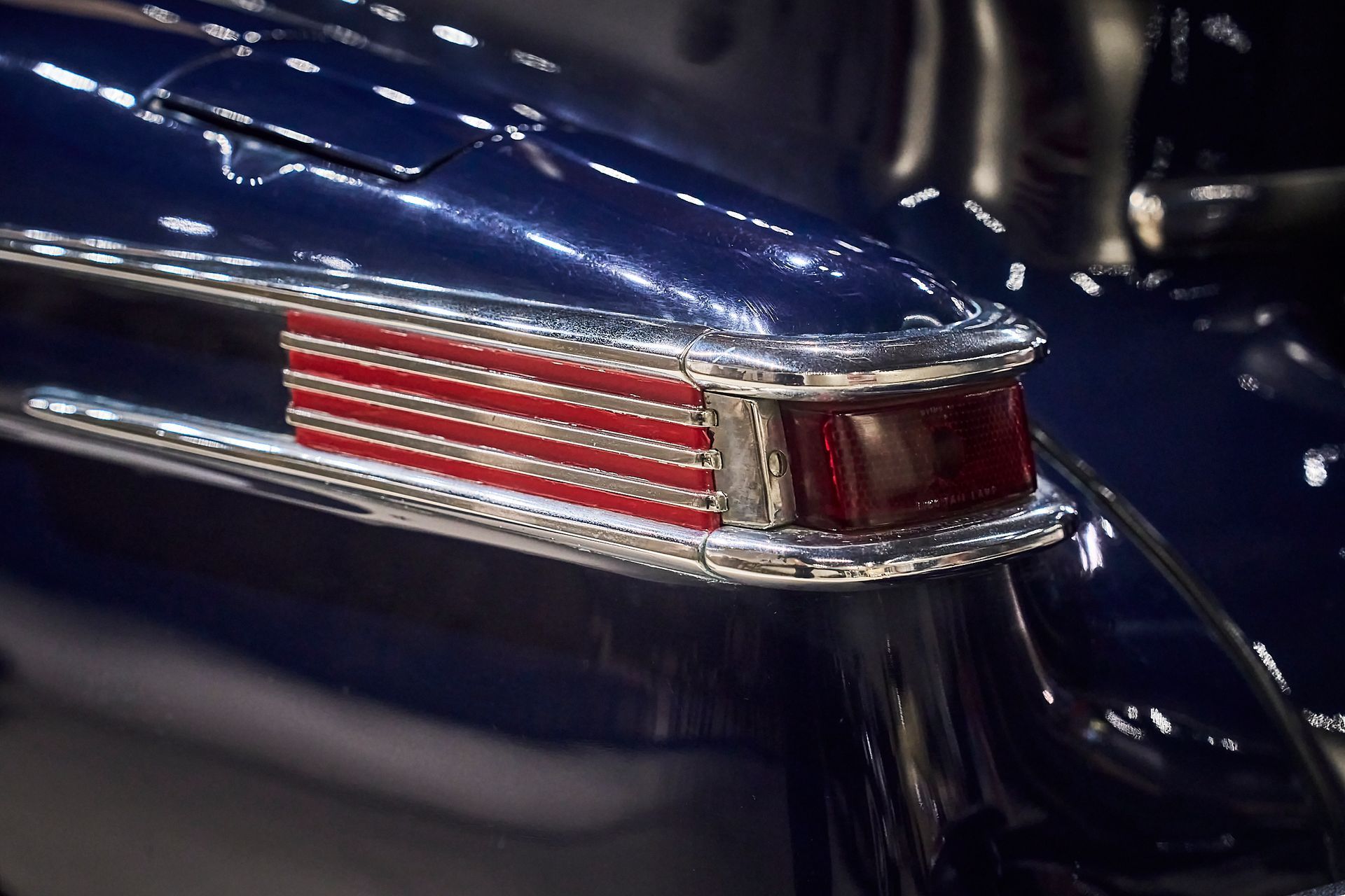 A close up of a blue car with a red white and blue tail light