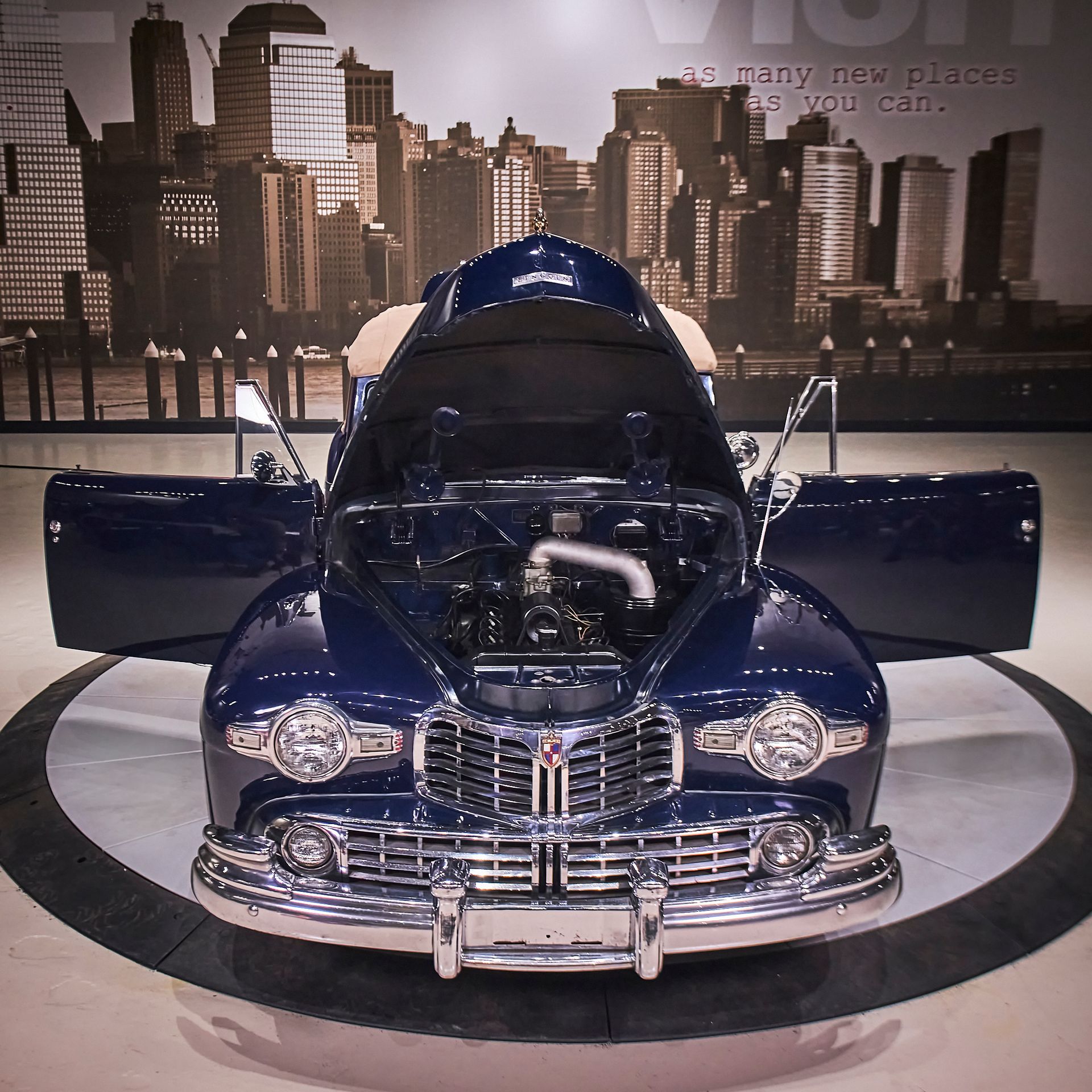 A blue car with the hood up and the doors open