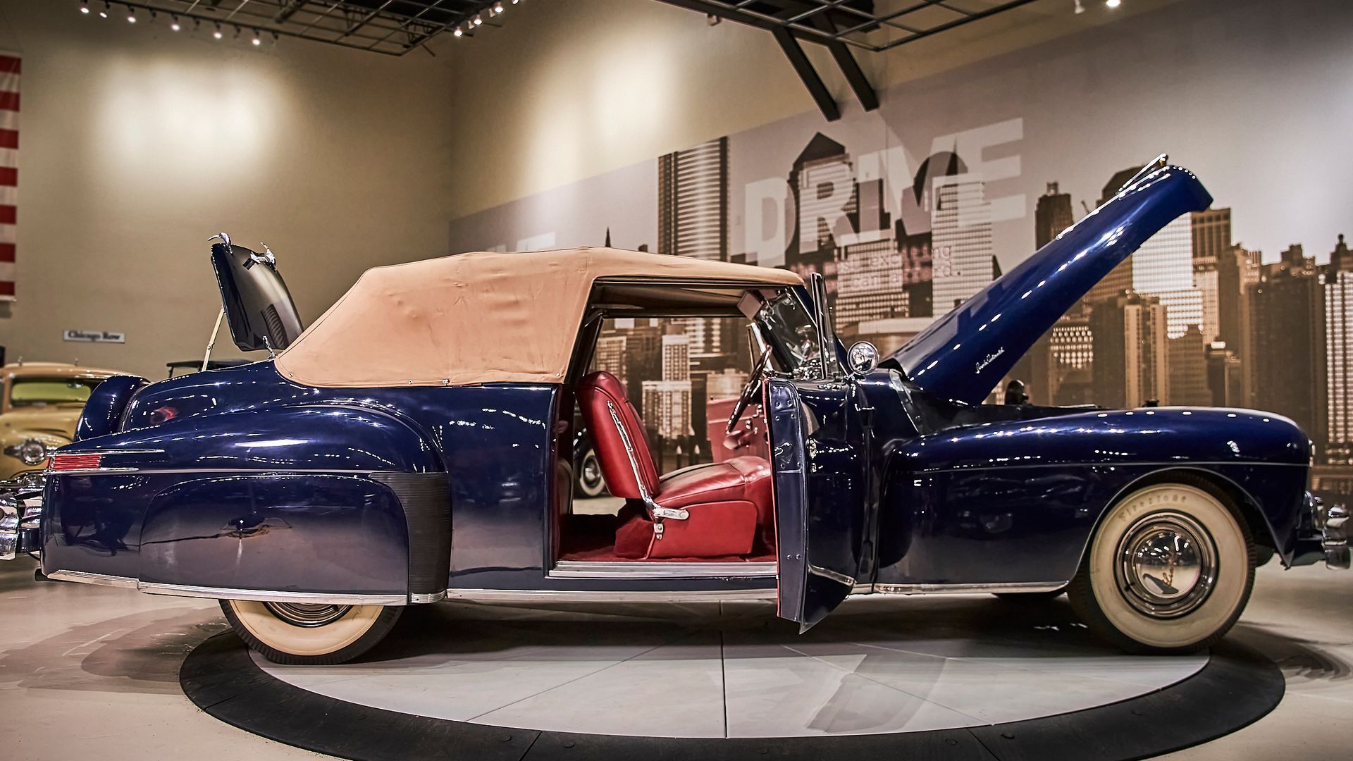 A blue car with the hood up is on display