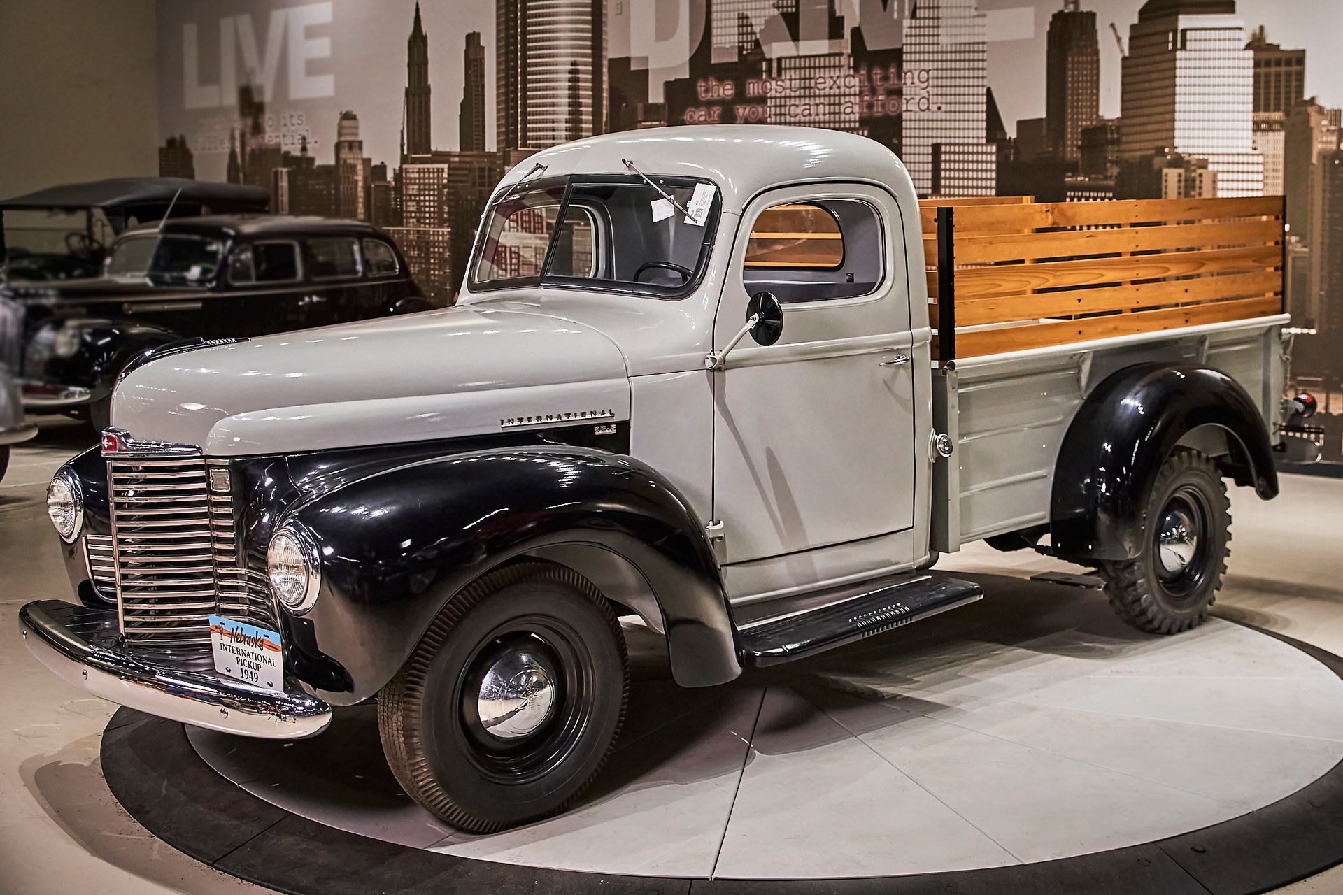 An old truck with a wooden bed is on display in a museum.