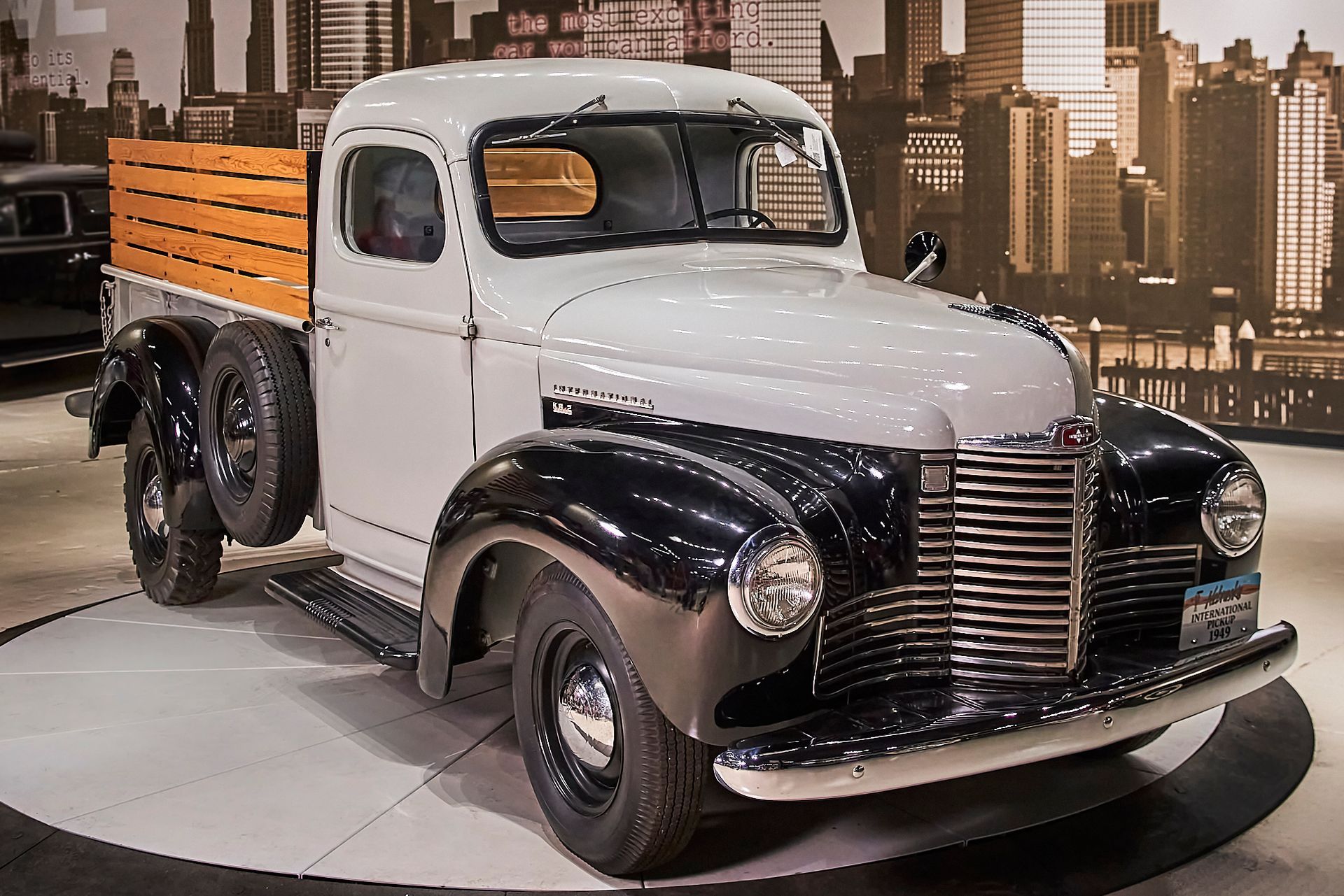 A black and white truck with a wooden bed is on display