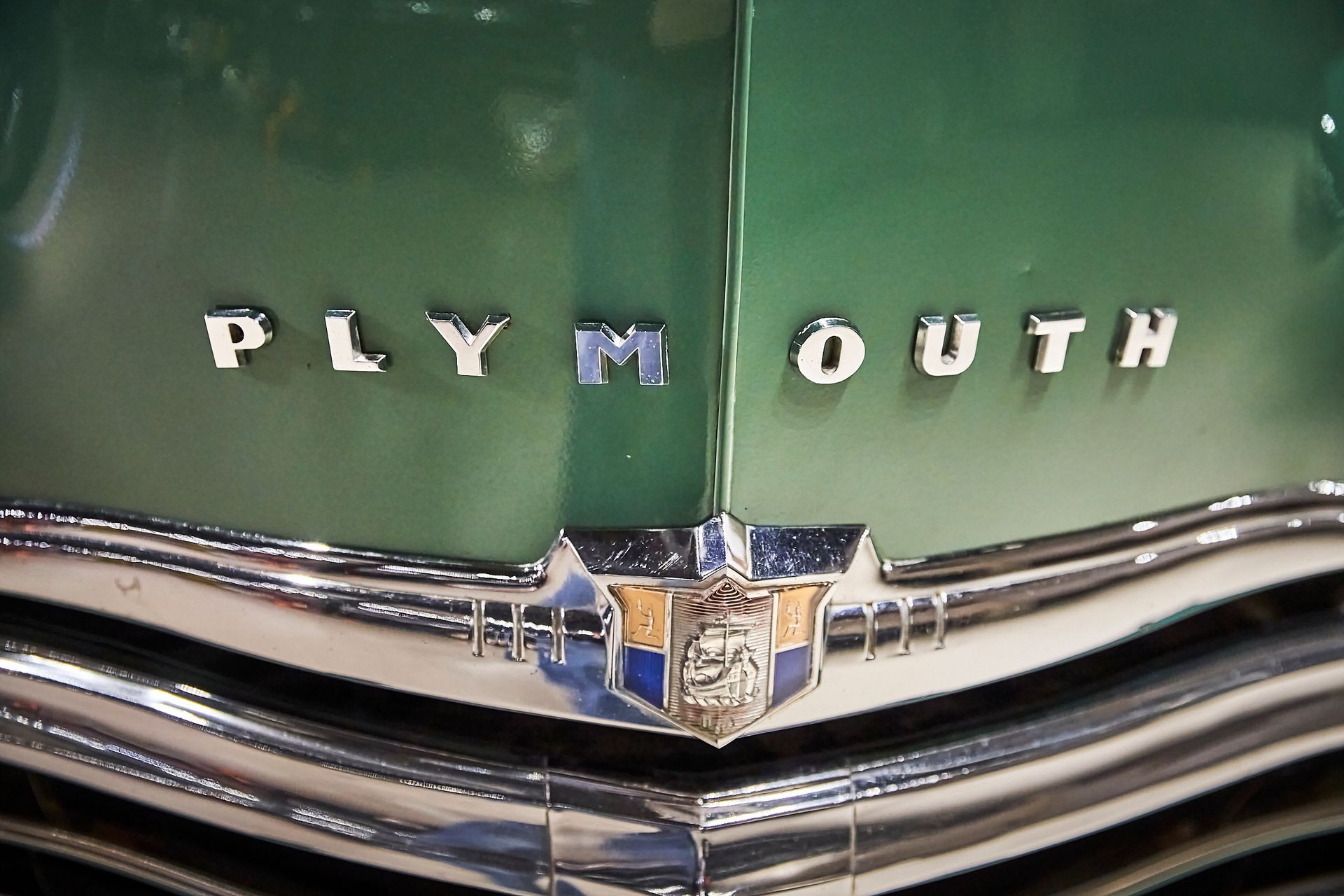The front of a green plymouth car with chrome trim