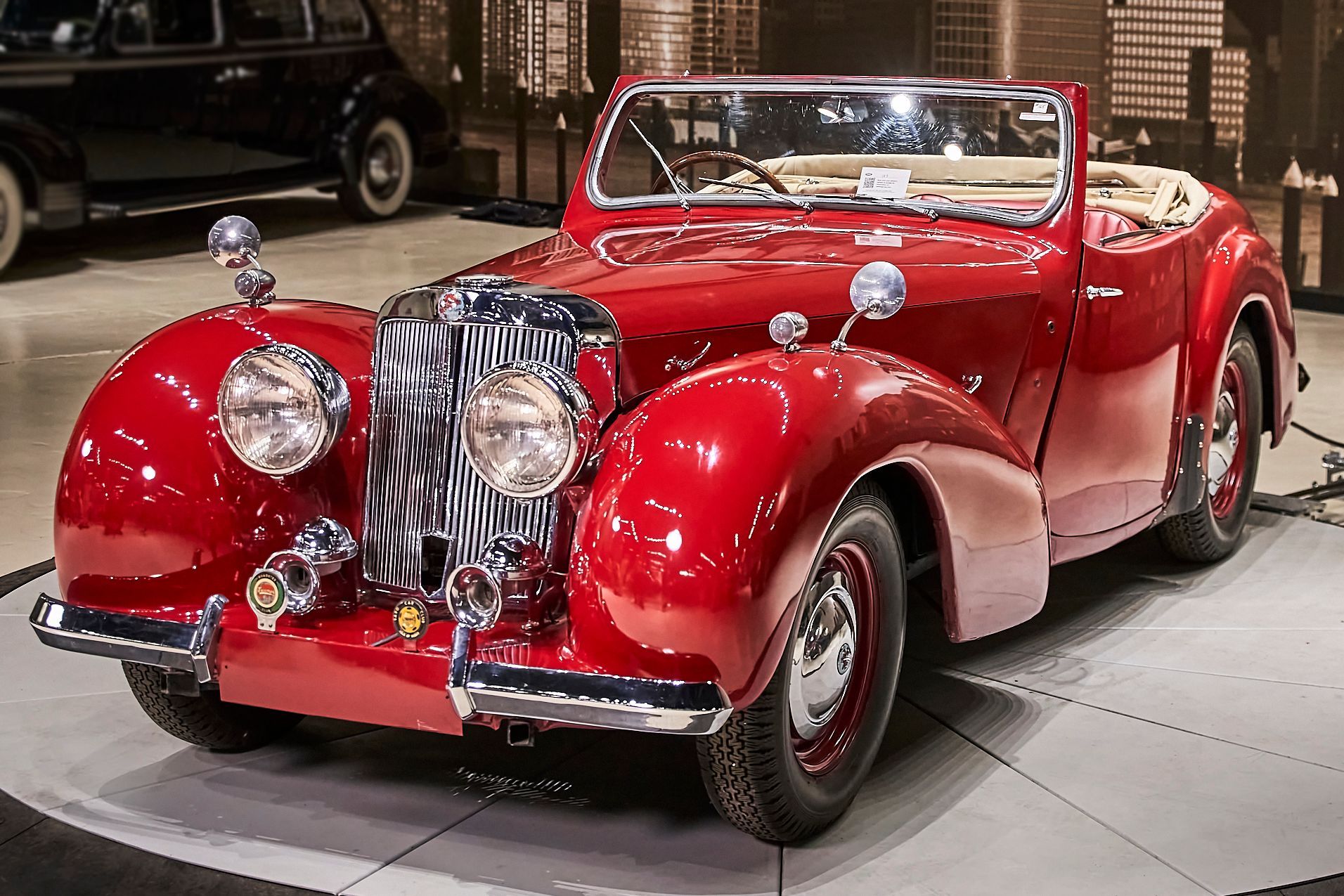 A red vintage car is parked in a garage