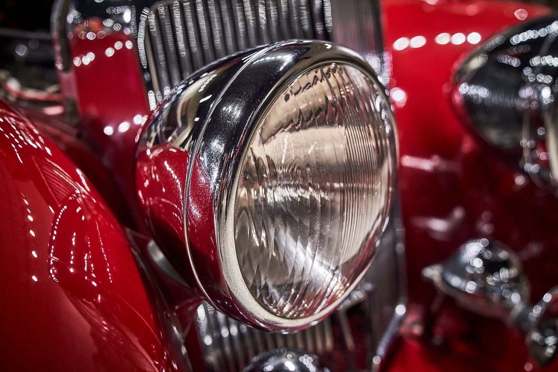 A close up of a red car 's headlight and grille.