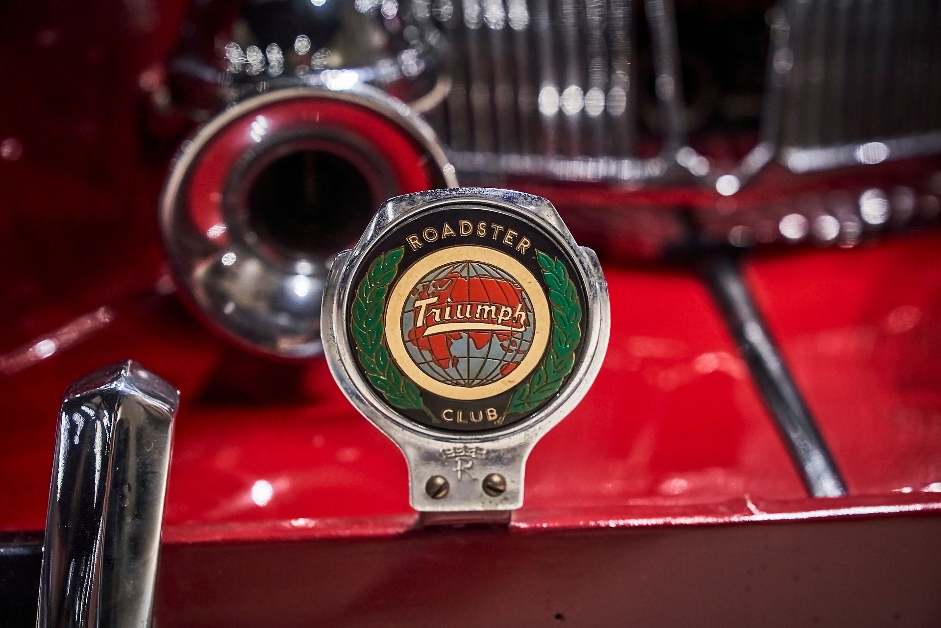 A close up of a badge on the front of a red car.