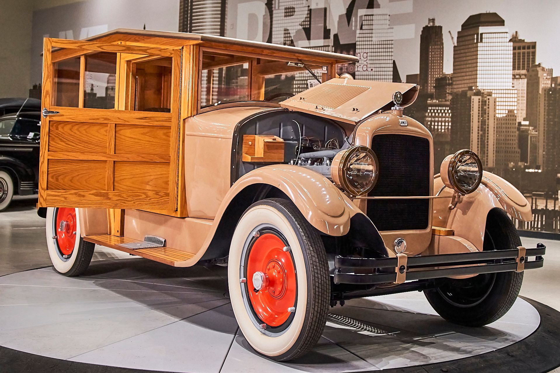 An old wooden wagon is parked in front of a city skyline