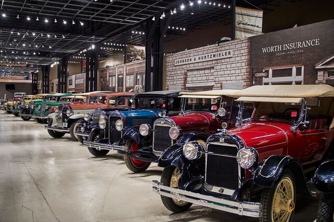 A row of old cars are parked in a garage.