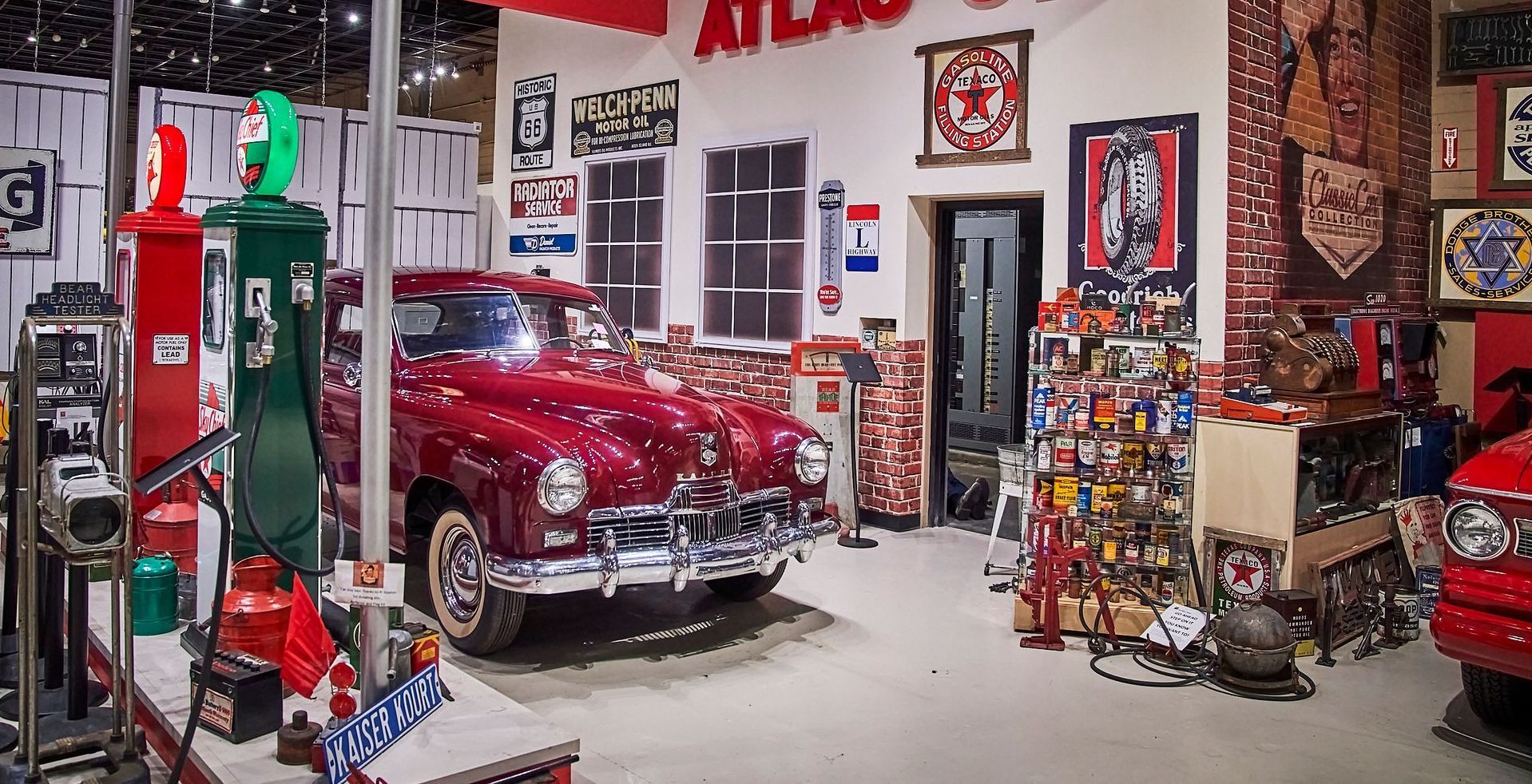 A red car is parked in a garage with a gas pump.