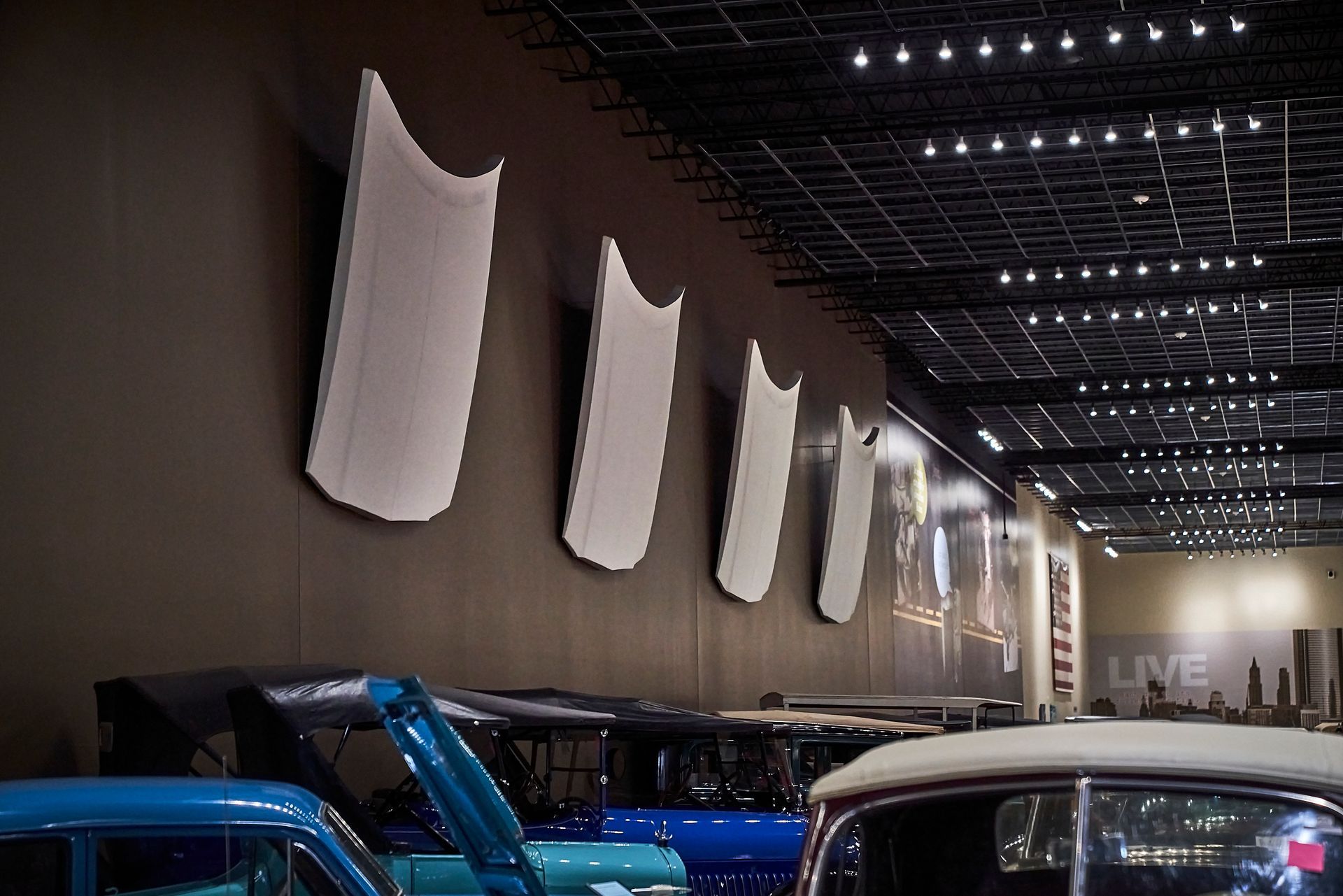 A row of blue and white cars are parked in a garage.