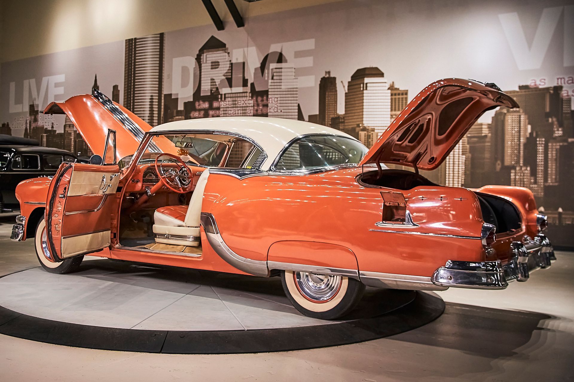 A red and white car with the hood open is on display