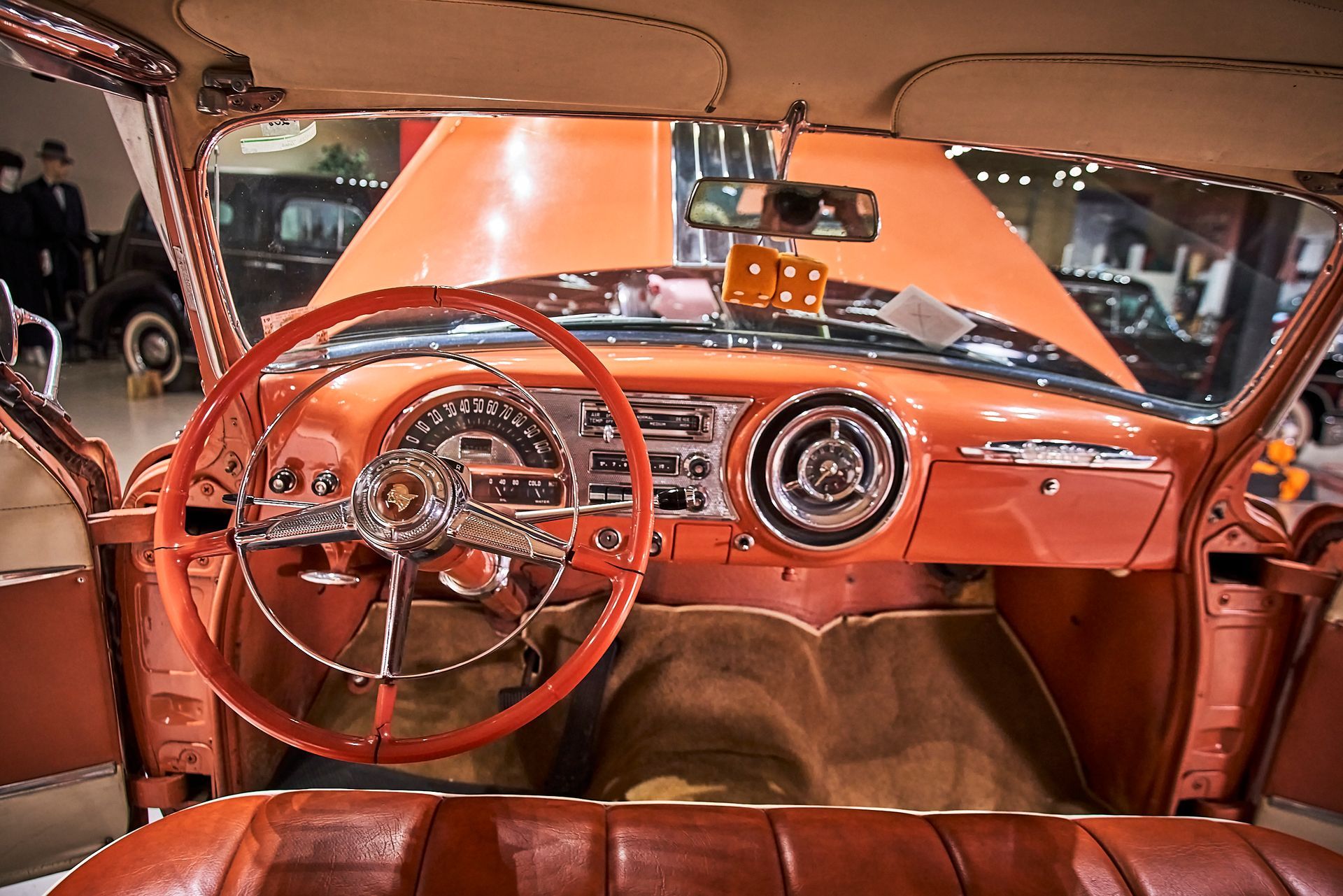 The interior of an old car with a red steering wheel