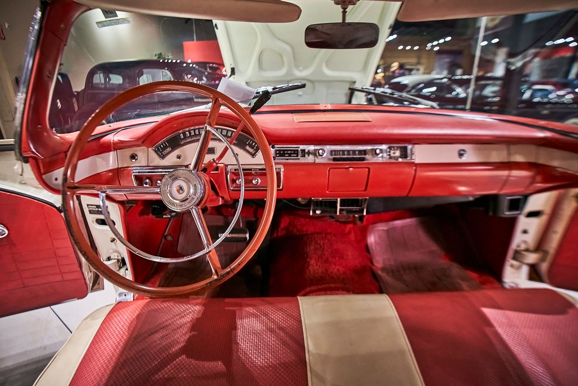 The interior of a red and white car with a wooden steering wheel.