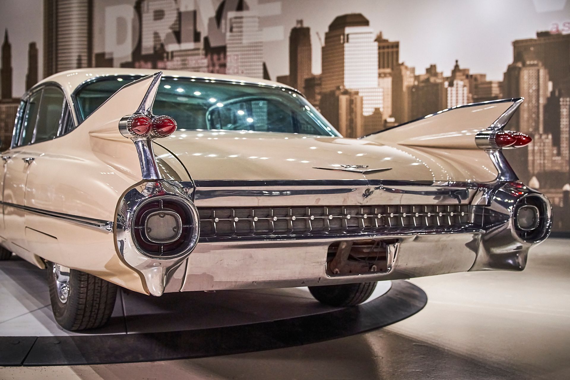 A white cadillac is parked in front of a city skyline.