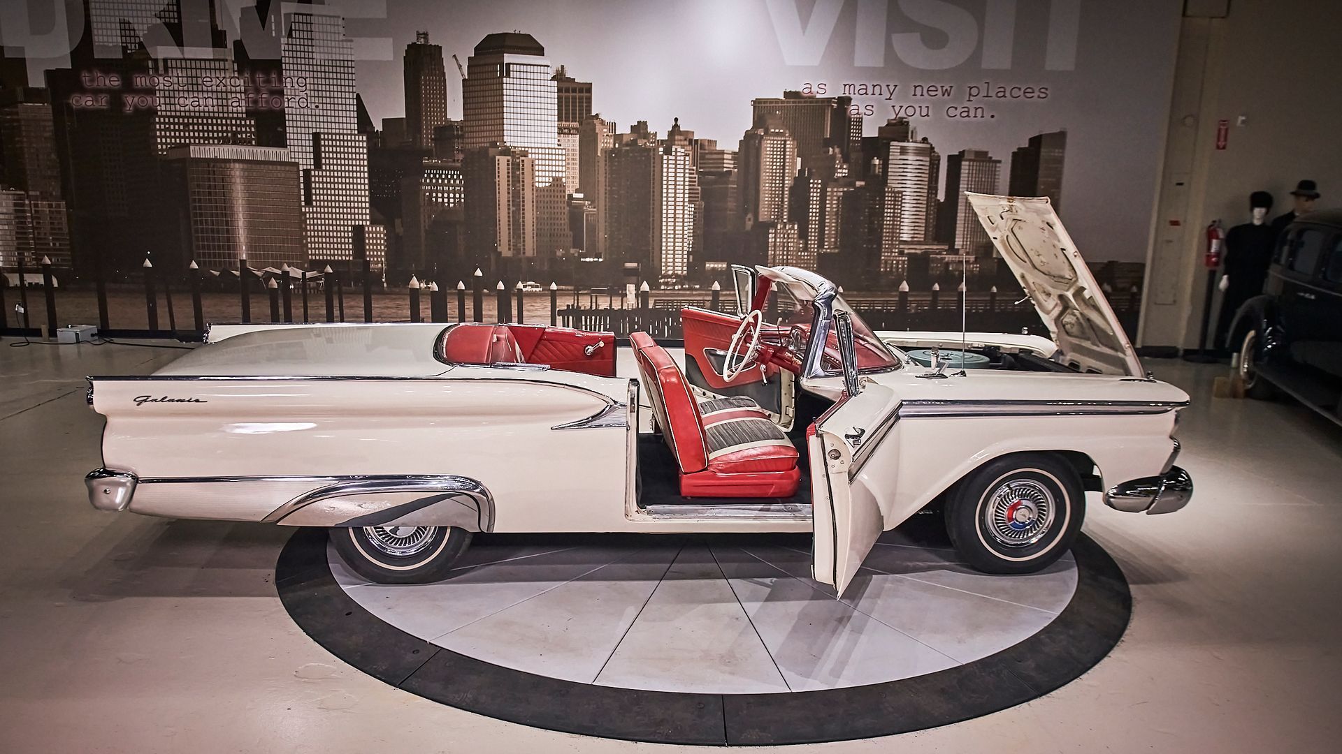 A white car with the hood open is parked in a garage.