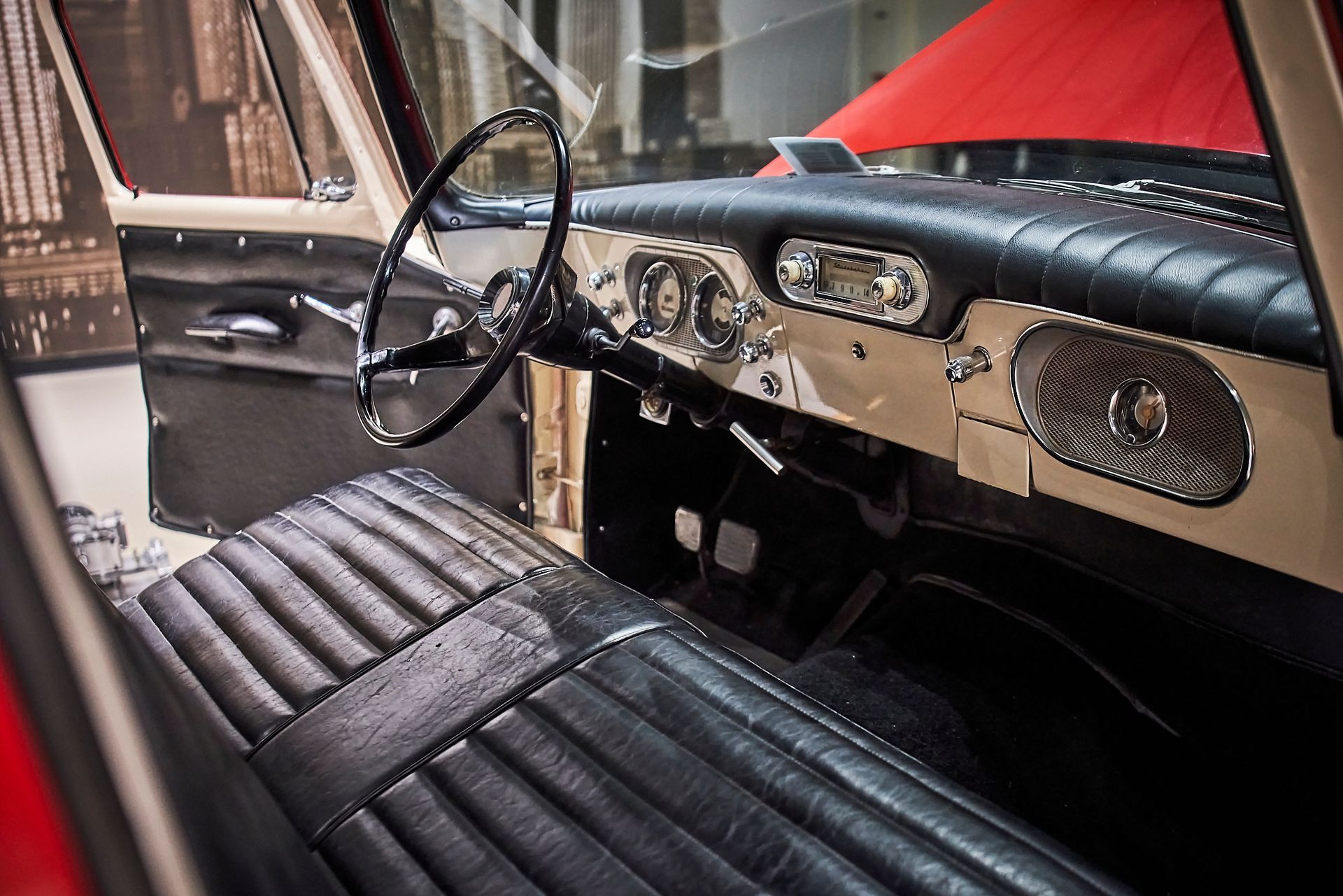 The interior of an old car with black leather seats and a steering wheel.
