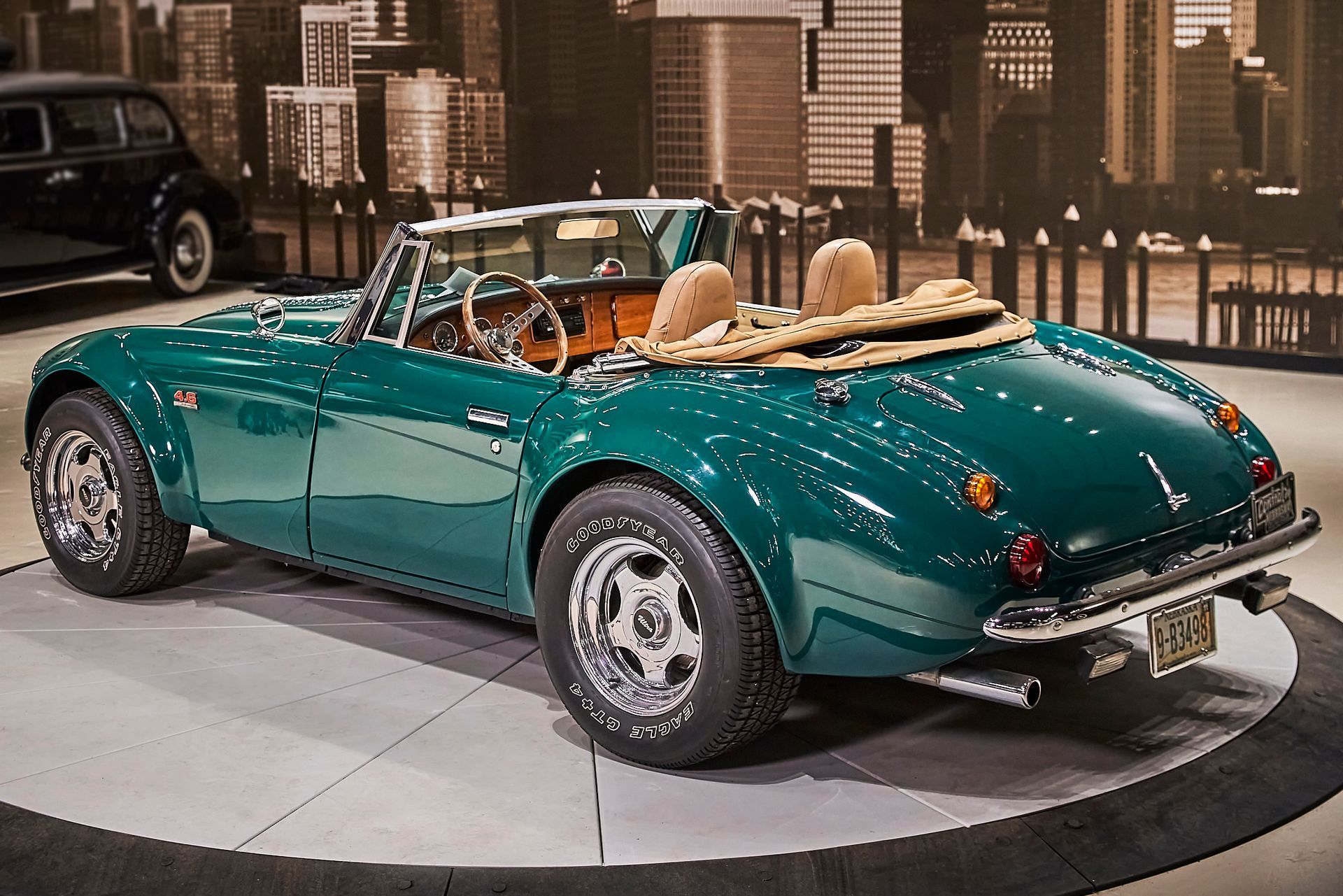A green sports car is parked in front of a city skyline