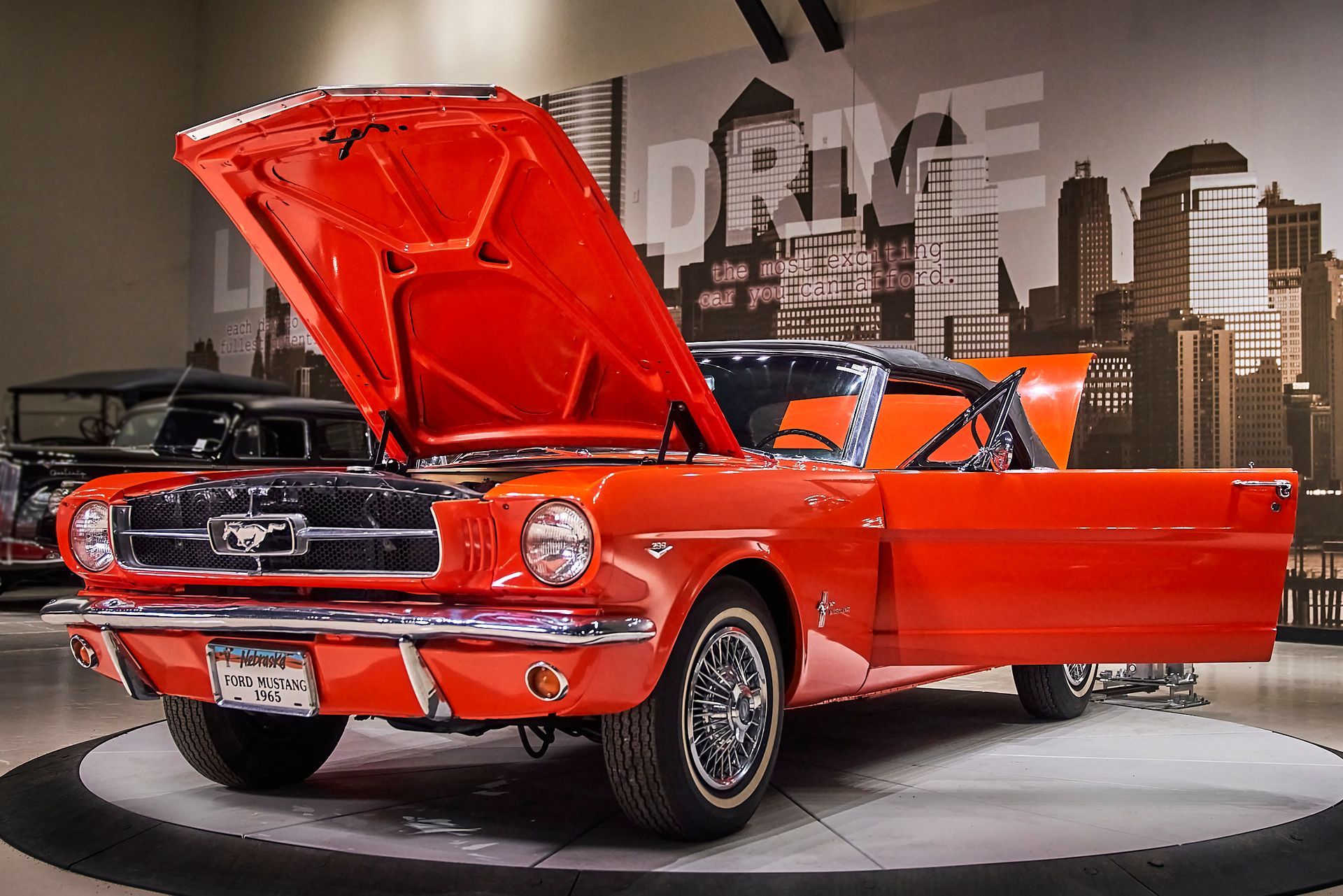A red mustang with the hood up is on display in a garage.