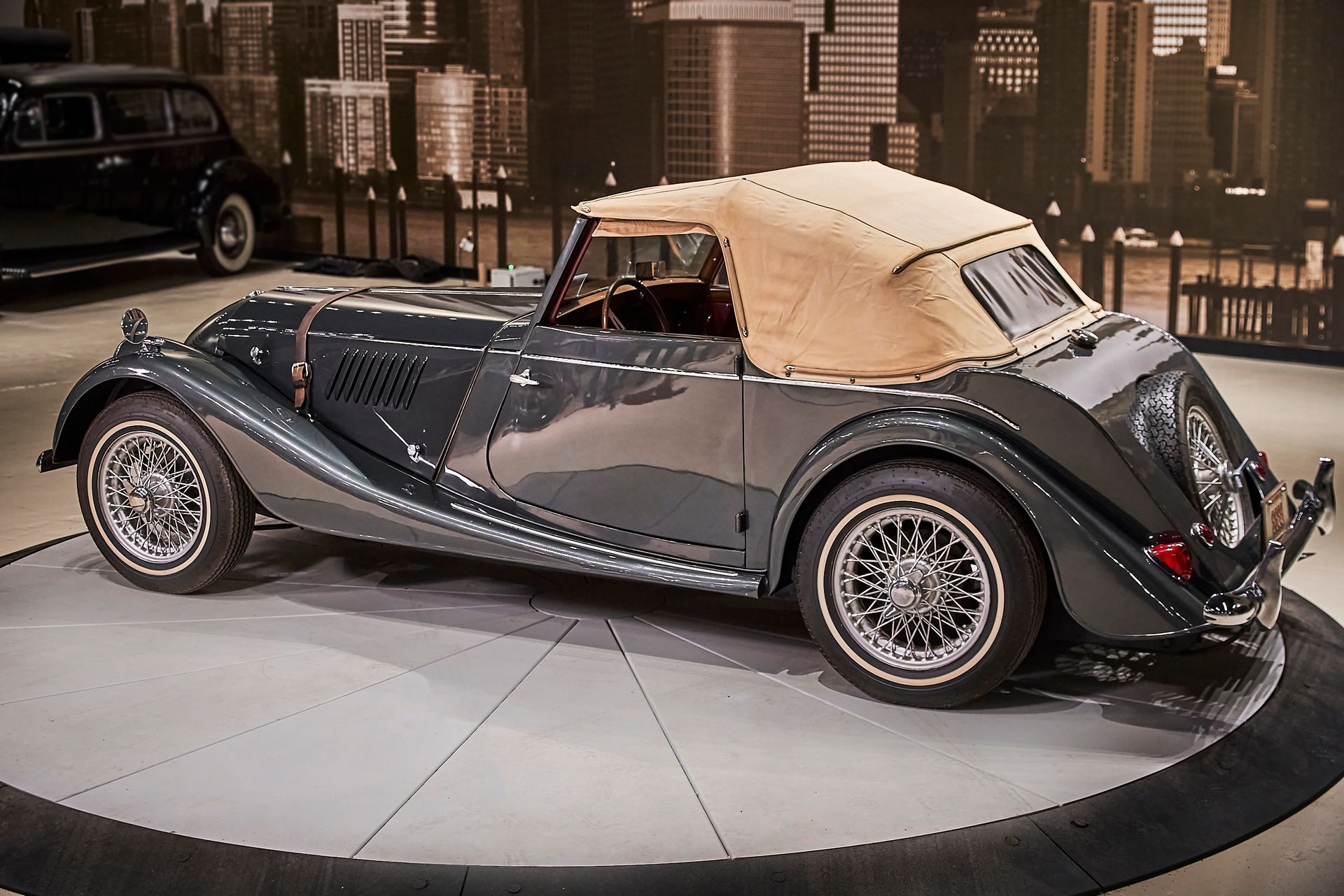 A black convertible car with a tan top is on display