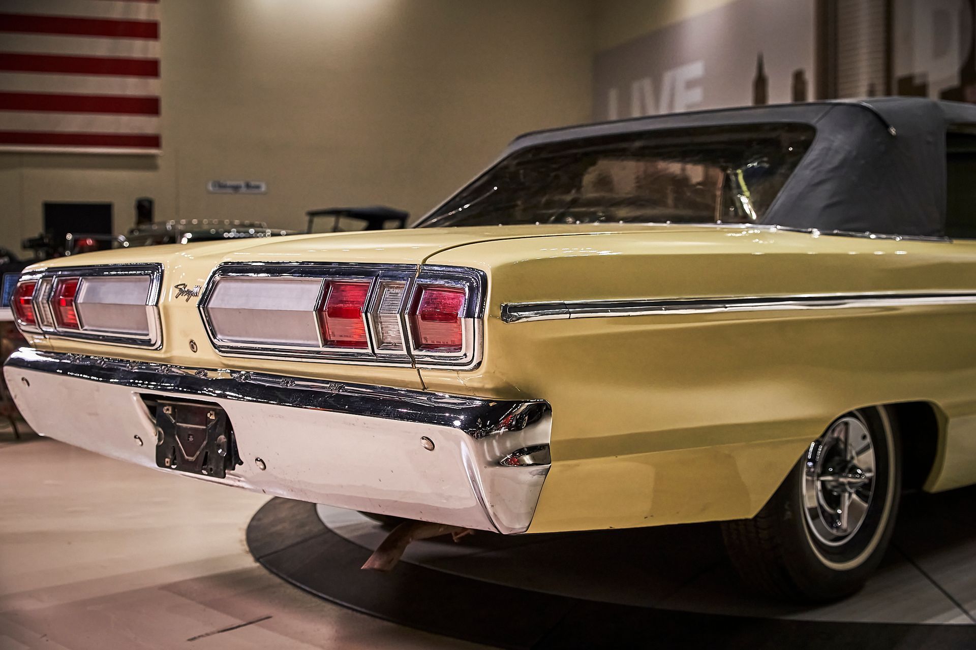 A yellow car is parked in front of an american flag