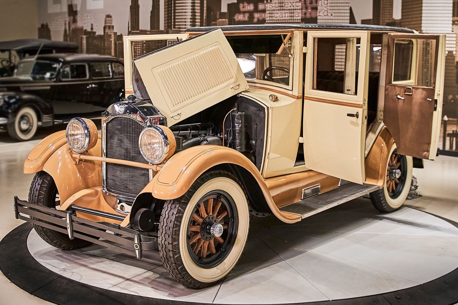 An old car with its hood open is on display in a museum.