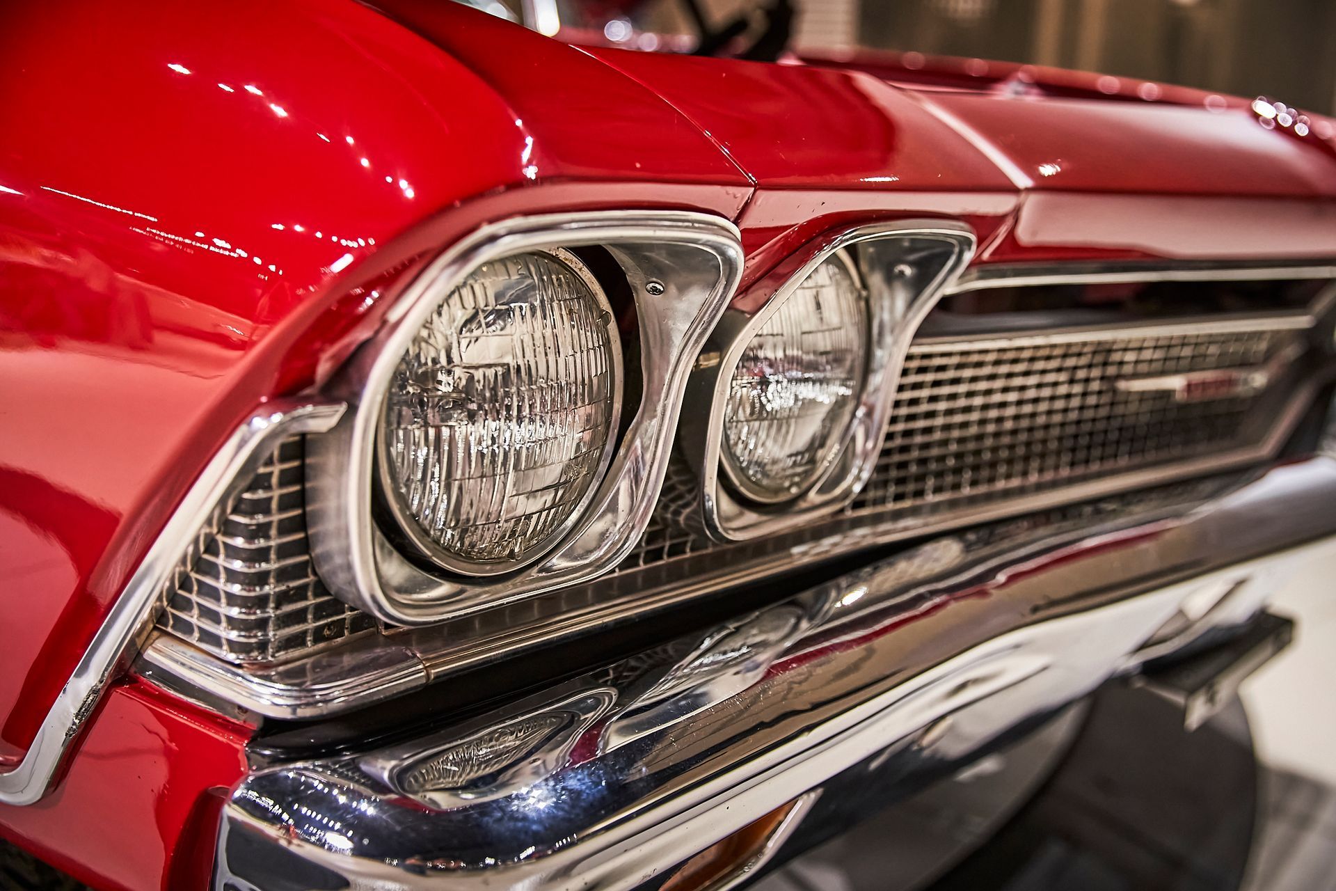 A close up of a red car 's headlights and grille.