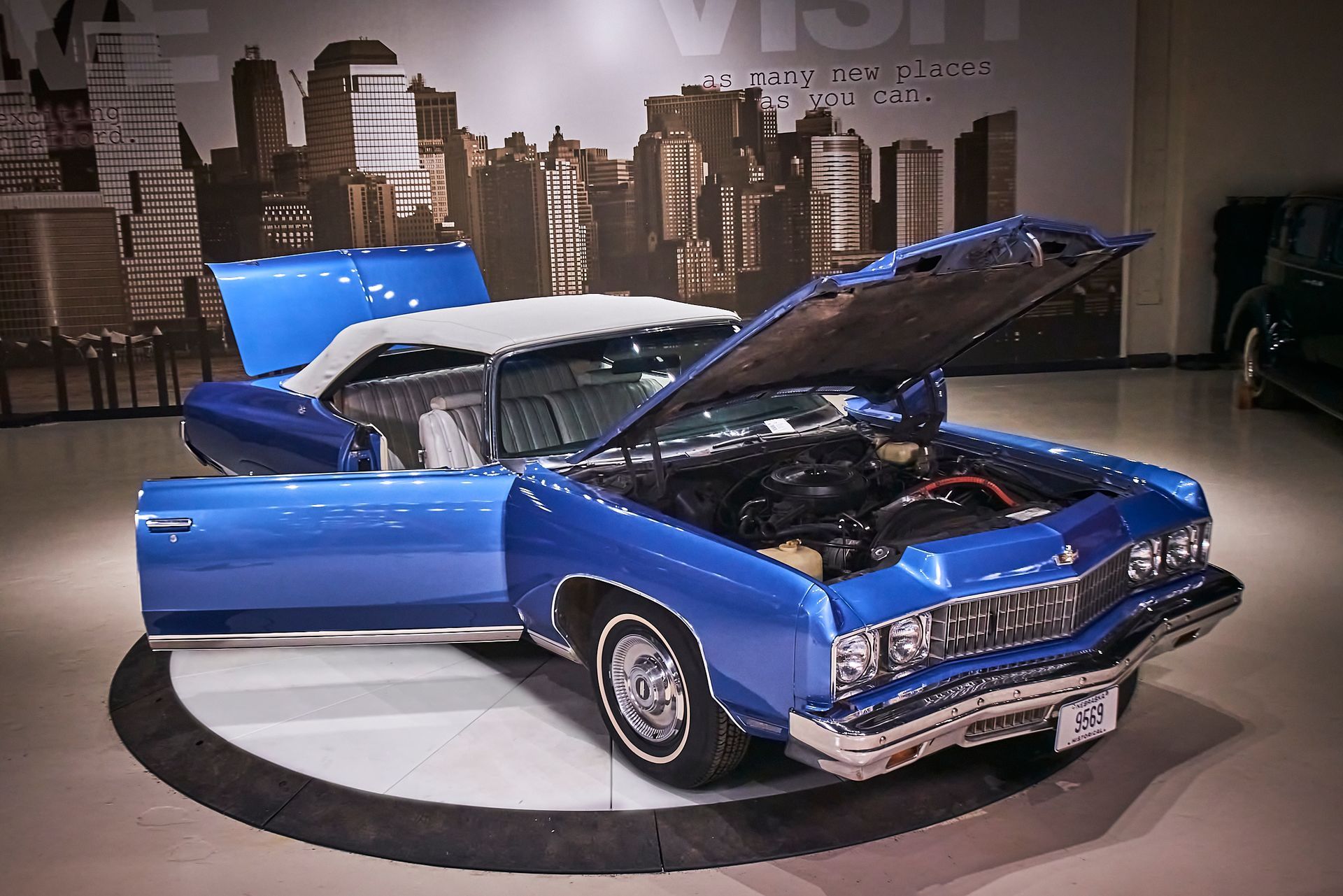 A blue car with the hood up and the doors open