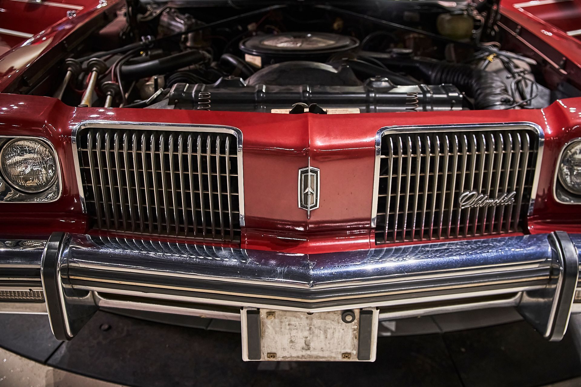 A red oldsmobile car with the hood open