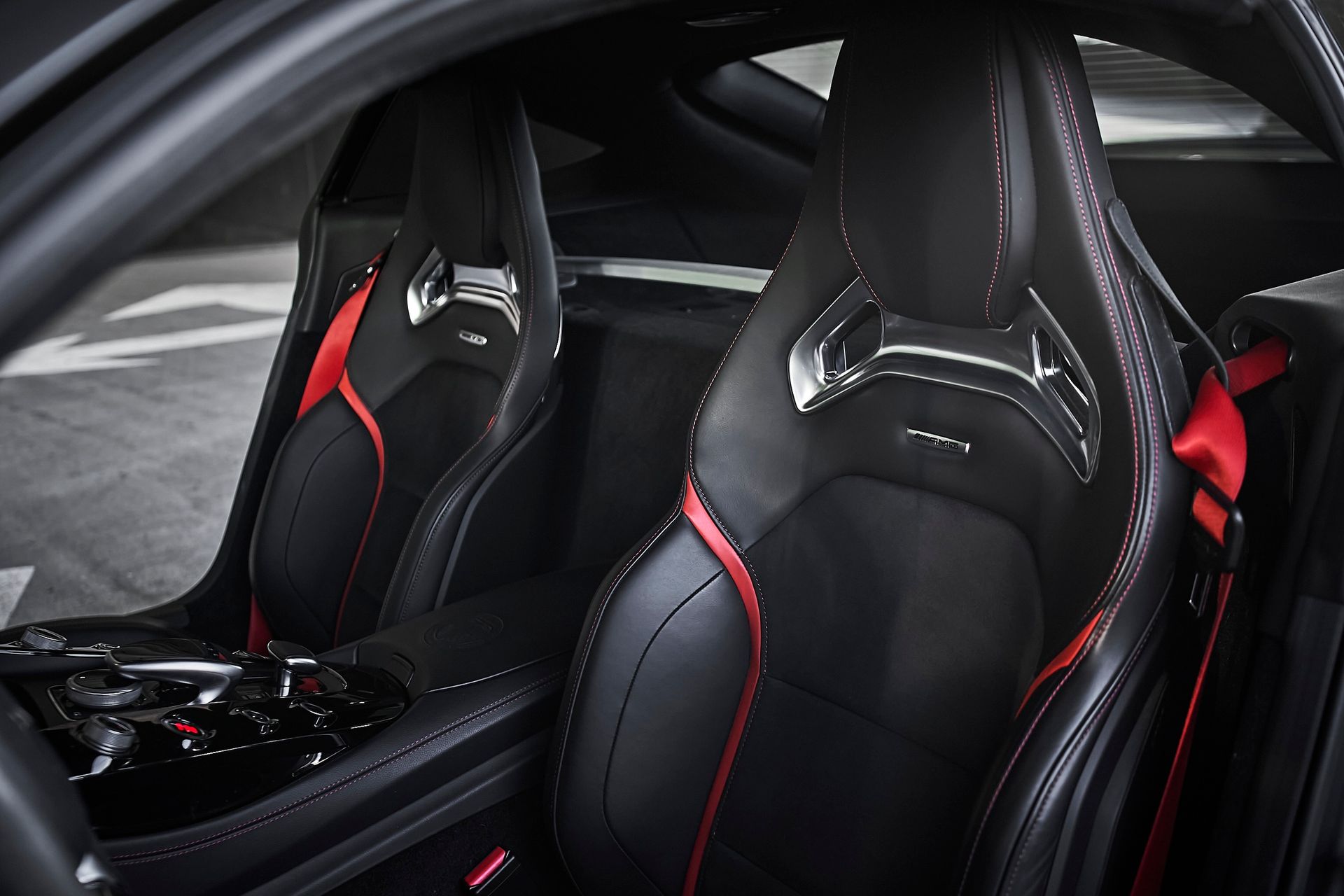 The inside of a black sports car with red seat belts