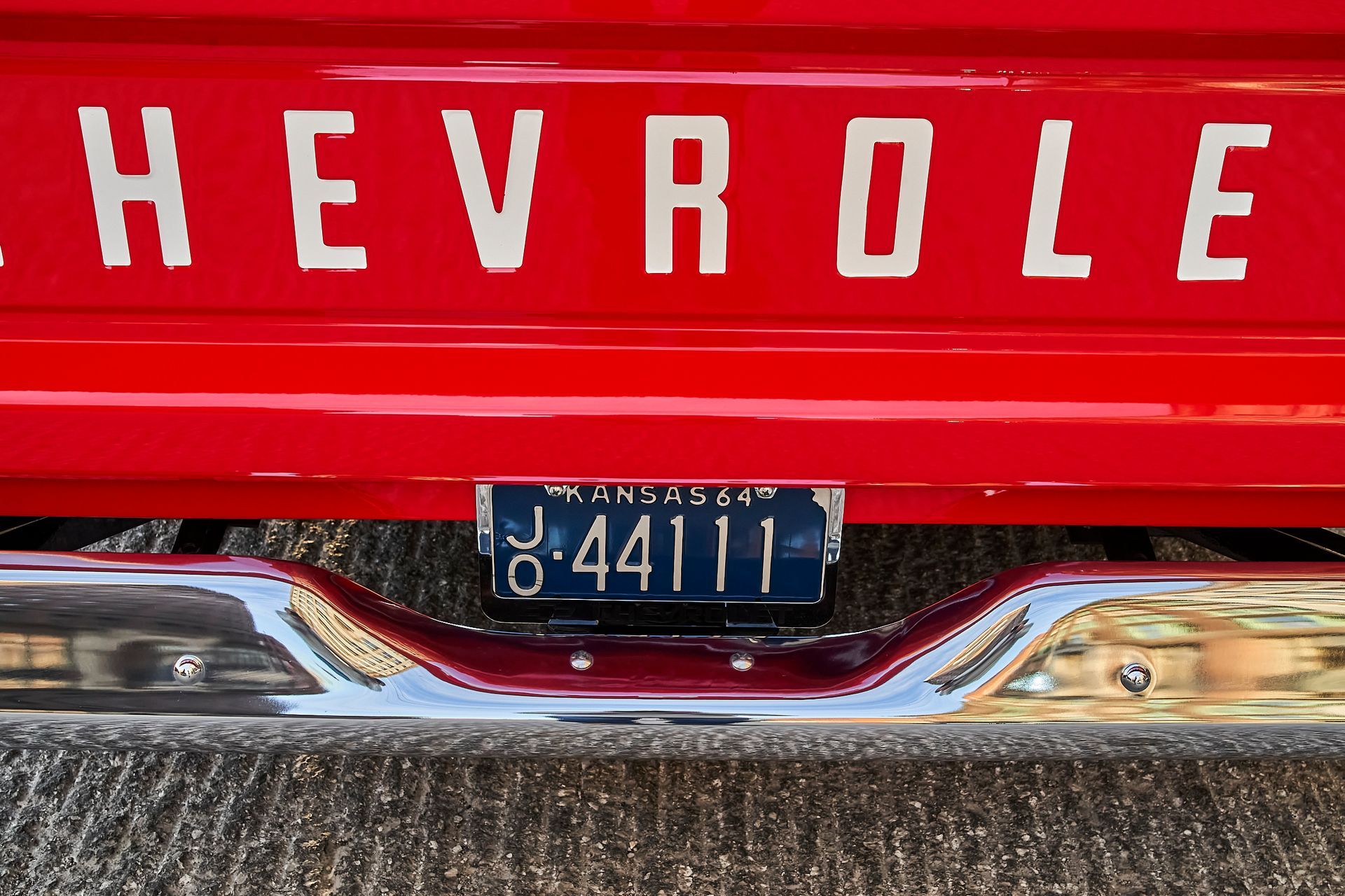 A red chevrolet truck with a blue license plate