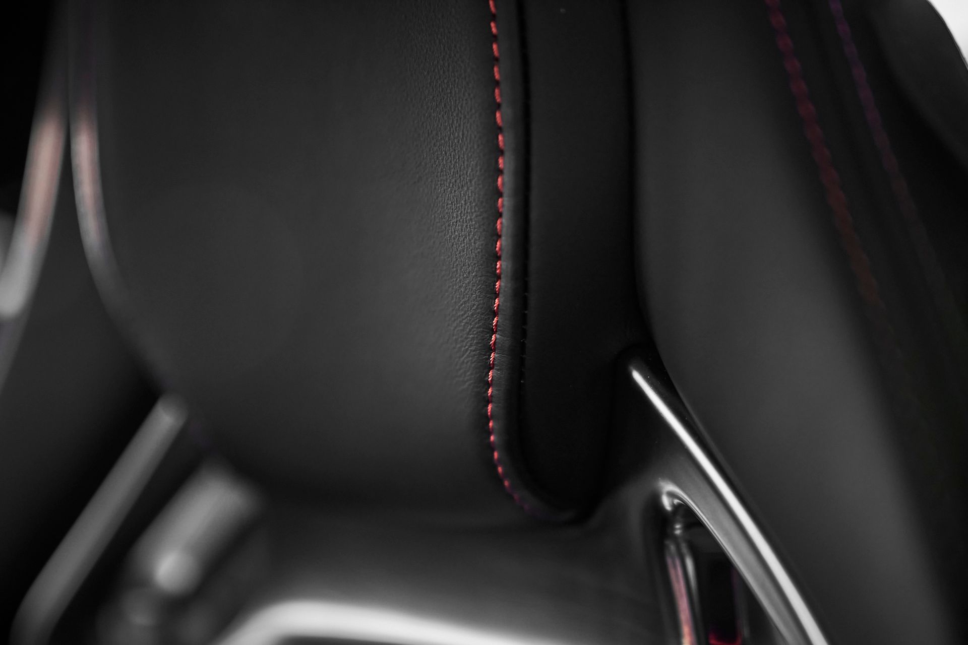 A close up of a car seat with a red stitching