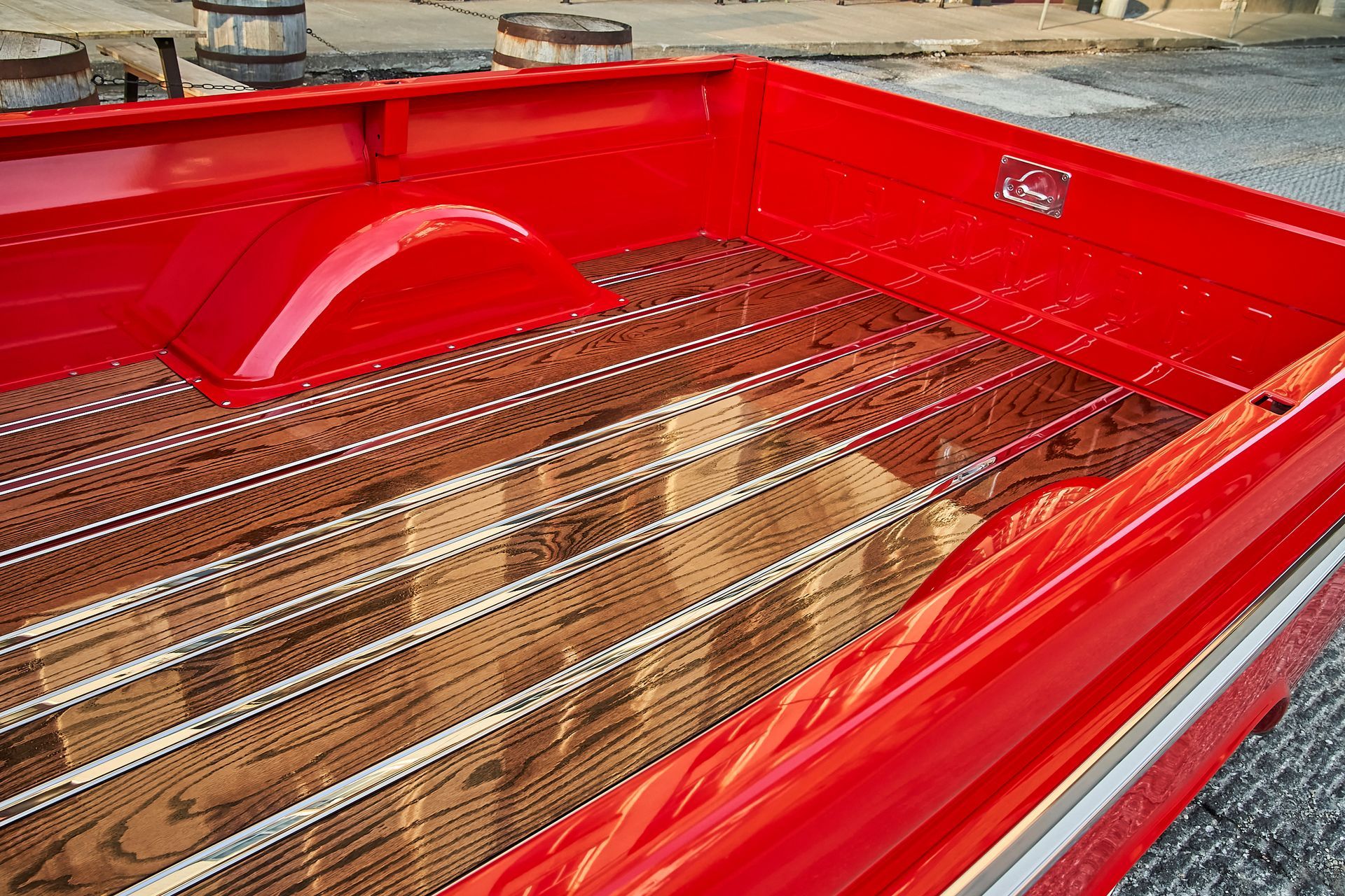 The back of a red truck with a wooden bed