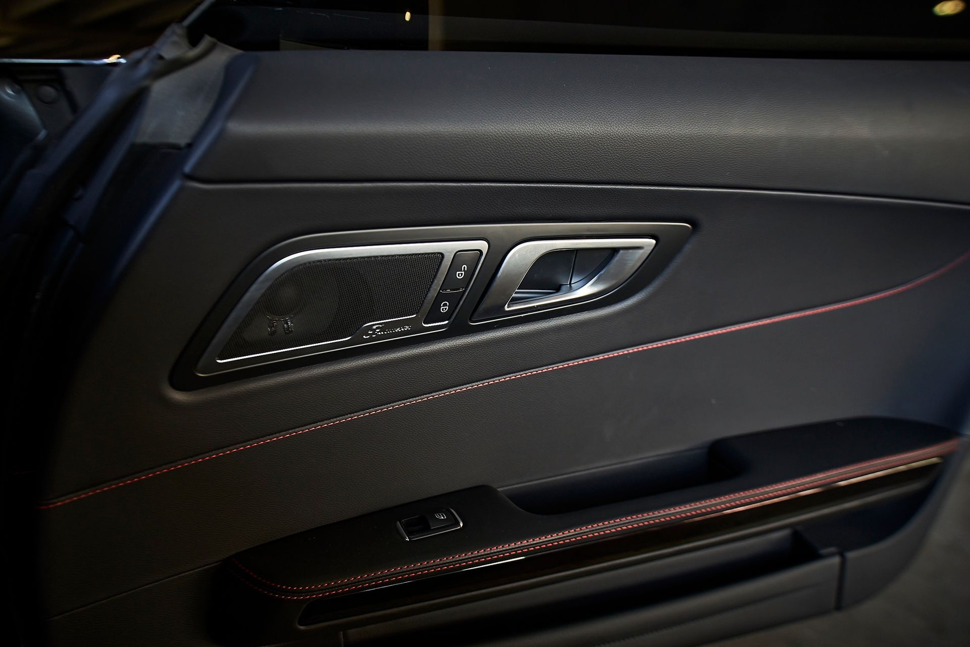 A close up of a car door with a red stitching