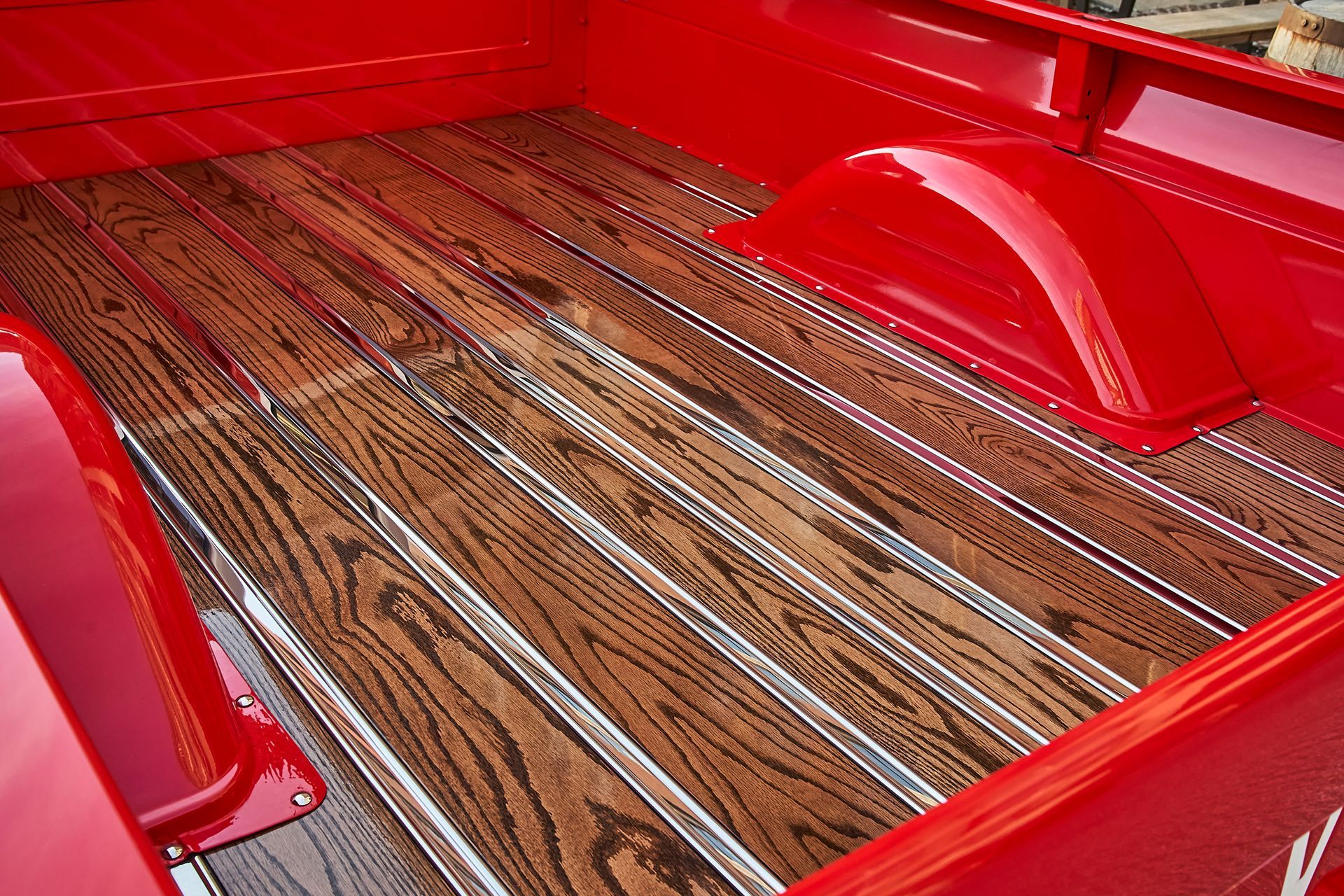 The back of a red truck with a wooden bed.