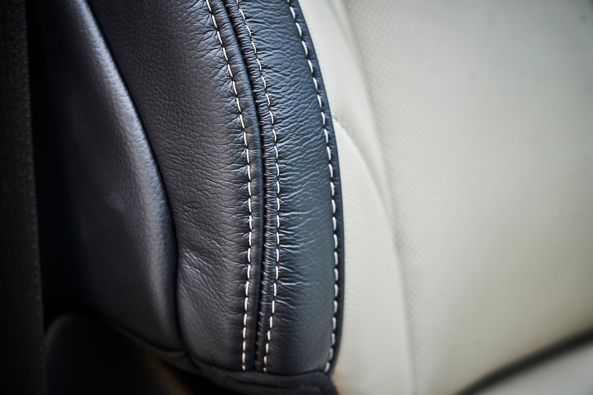 A close up of a black and white leather seat with white stitching