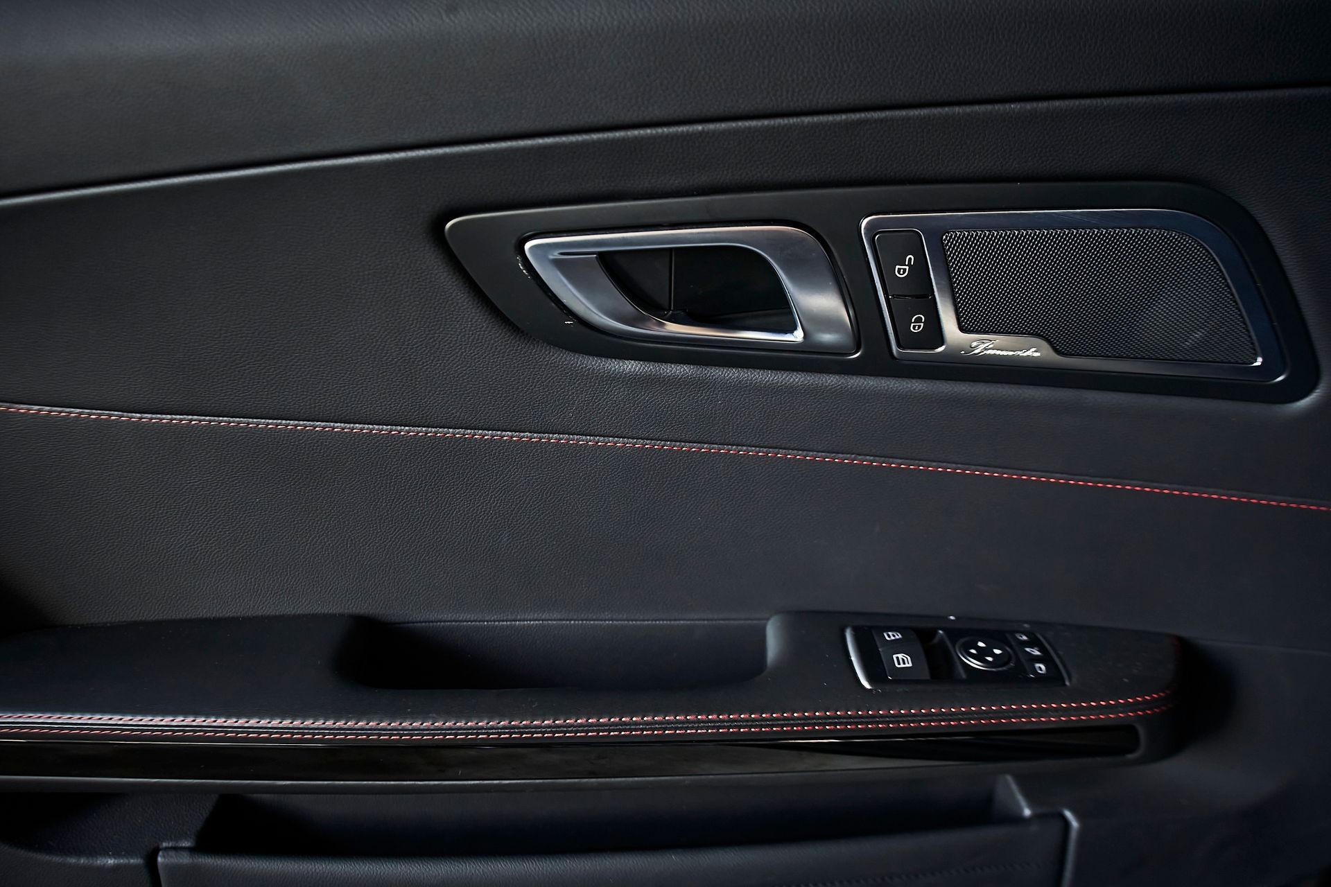 A close up of a car door with a red stitching