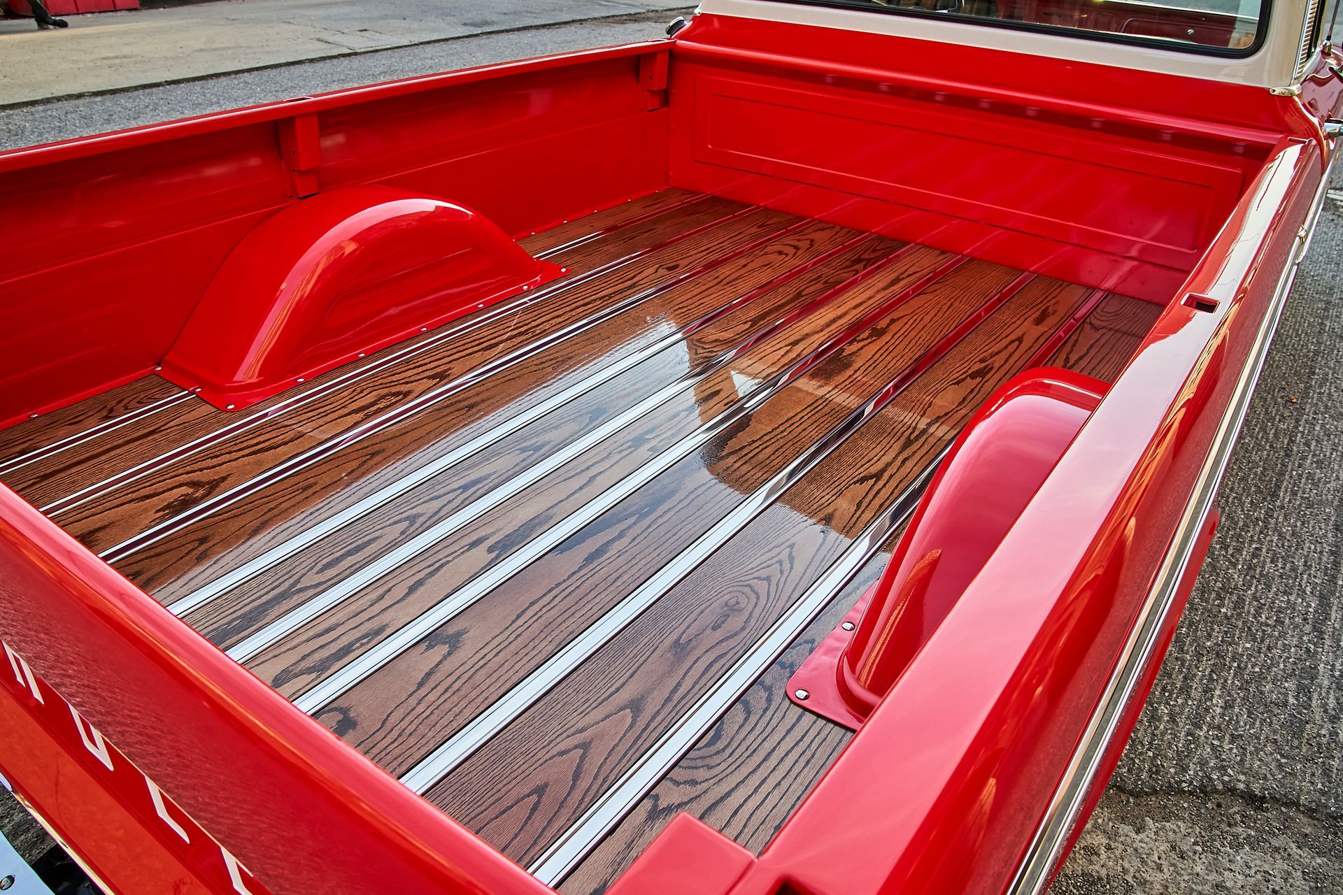 The back of a red truck with a wooden bed.