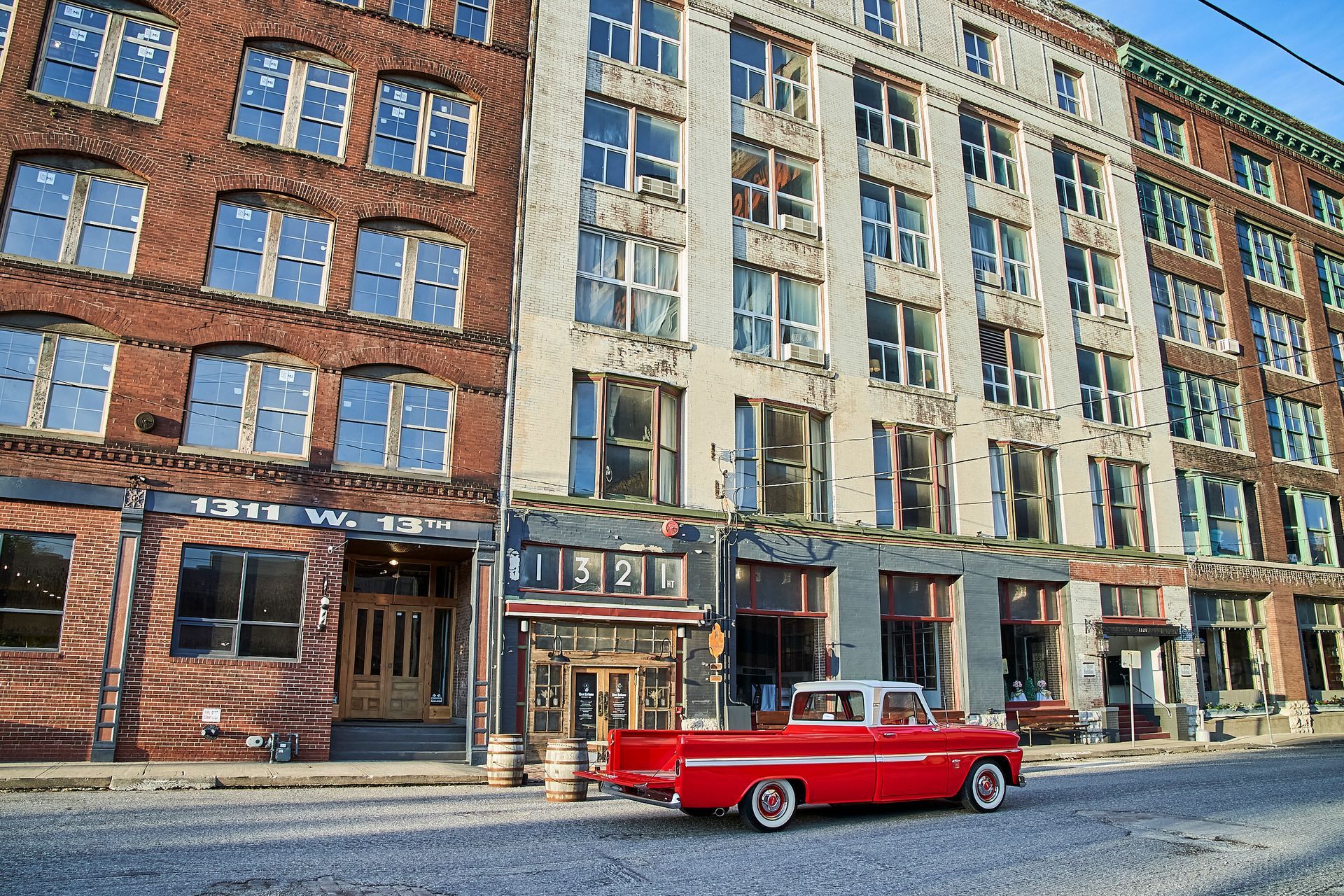 A red truck is parked in front of a large building.