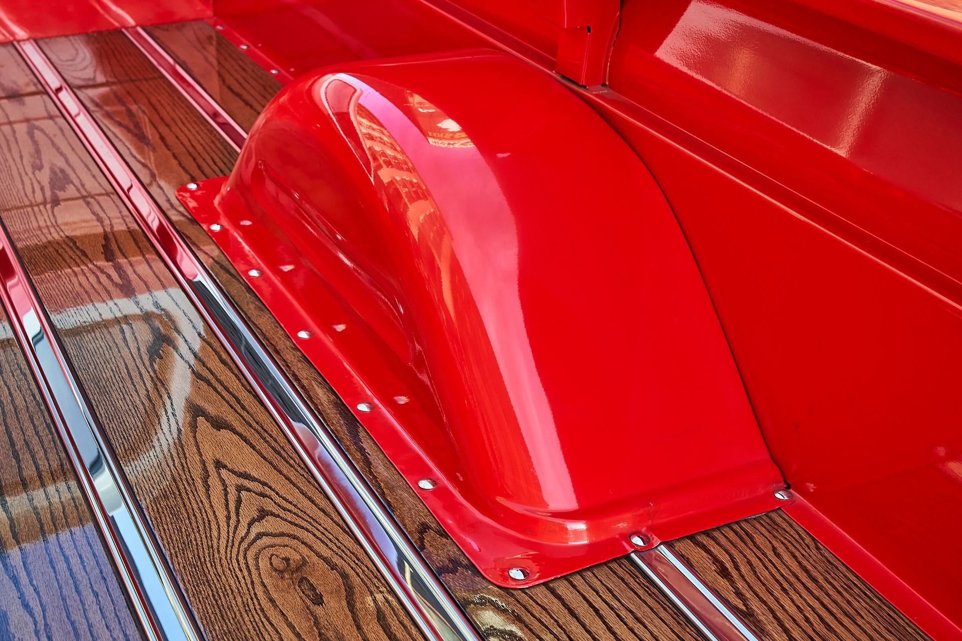 A red truck with a wooden bed and a red fender.
