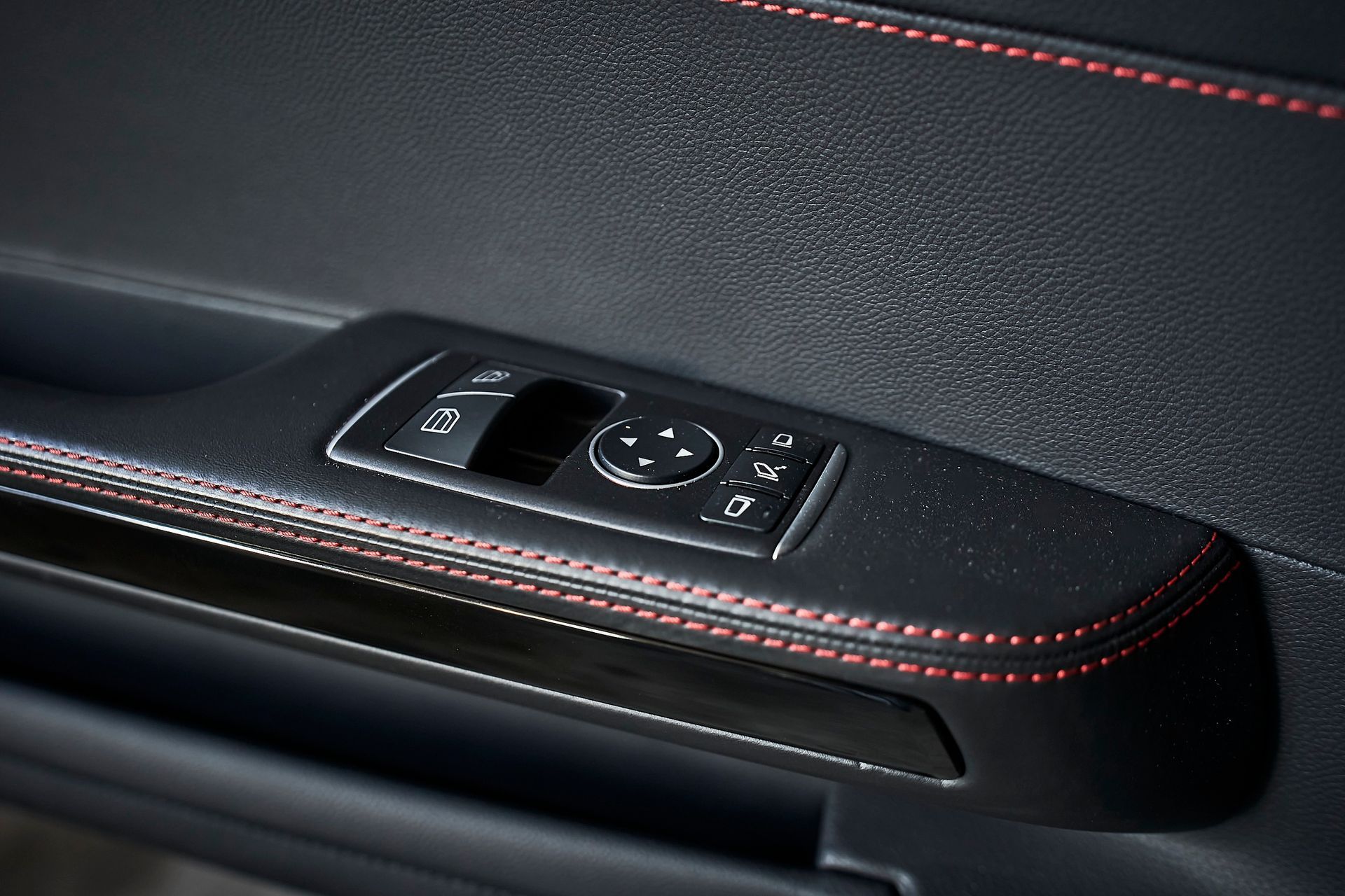 A close up of a car door with a red stitching