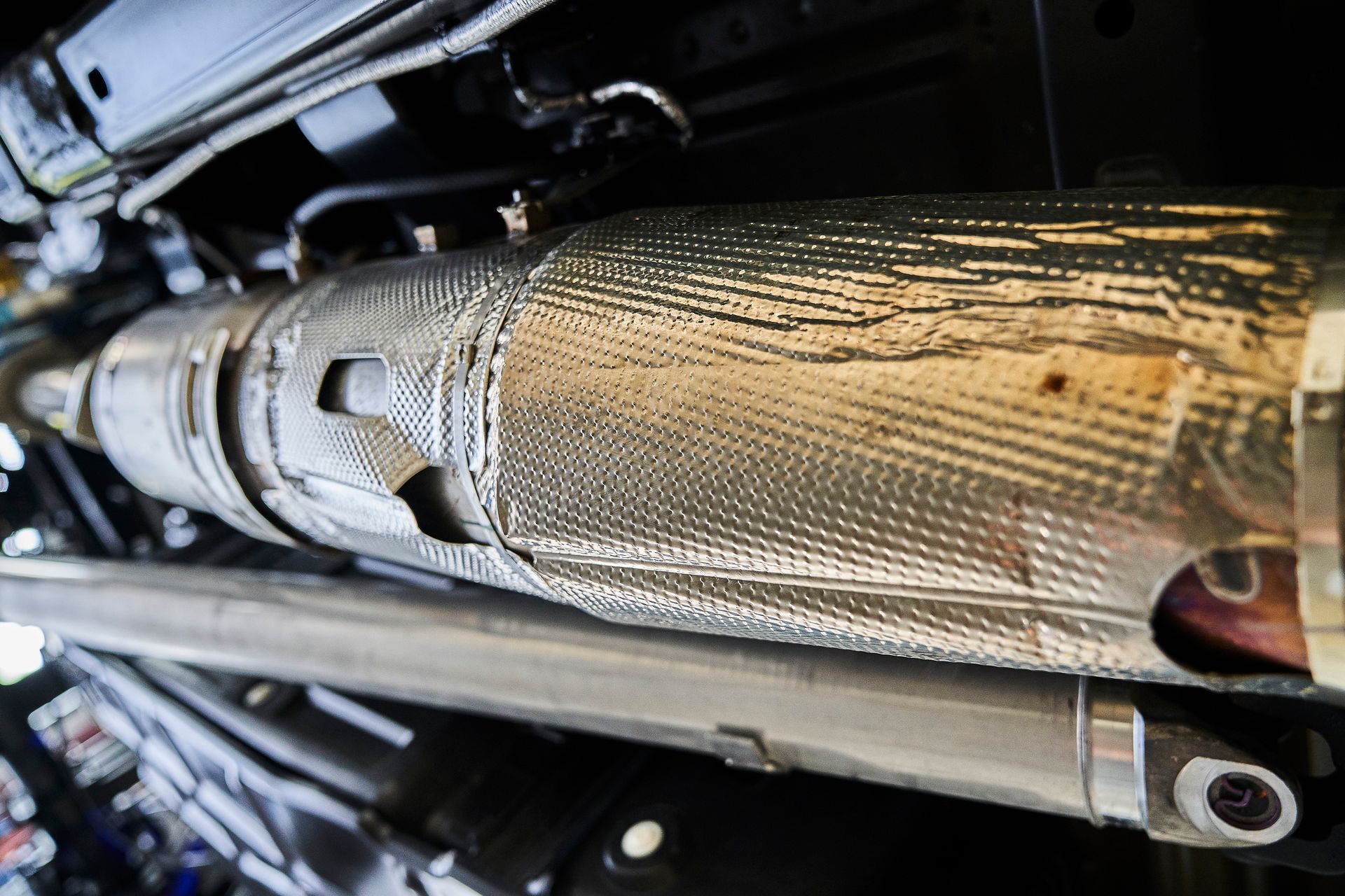 A close up of a exhaust pipe on the underside of a car.