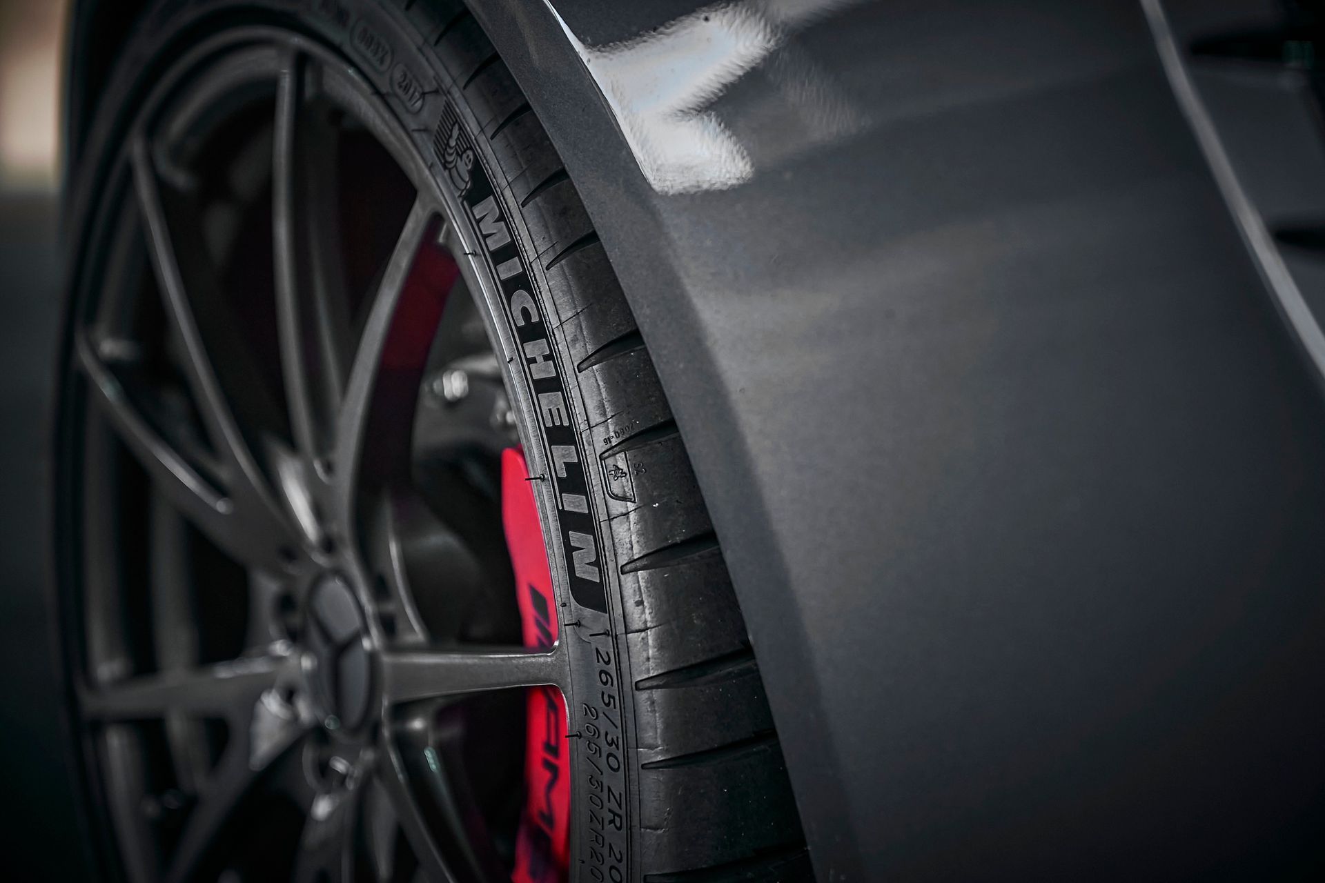 A close up of a tire on a car with red brake calipers.