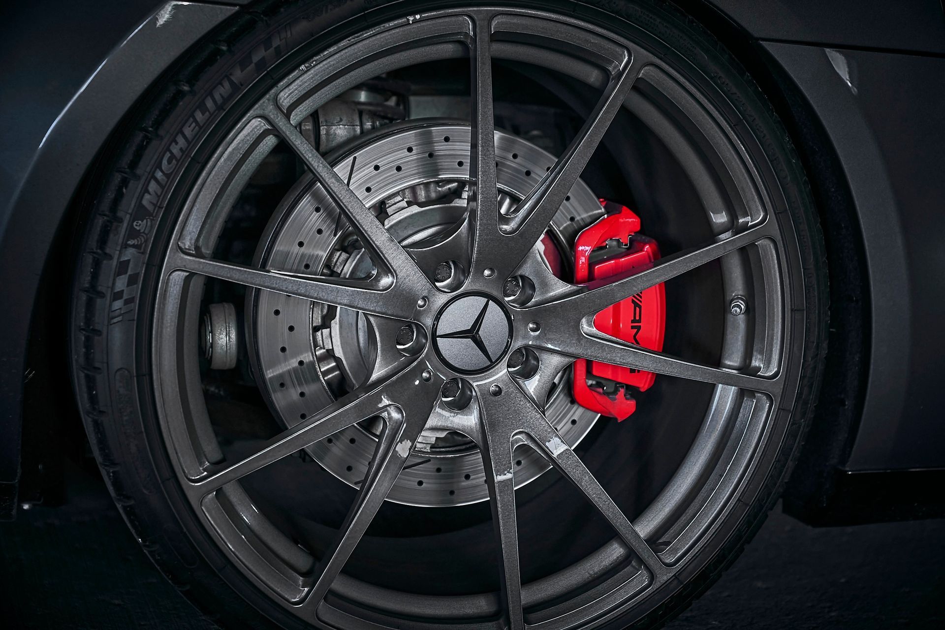 A close up of a car wheel with a red brake caliper.