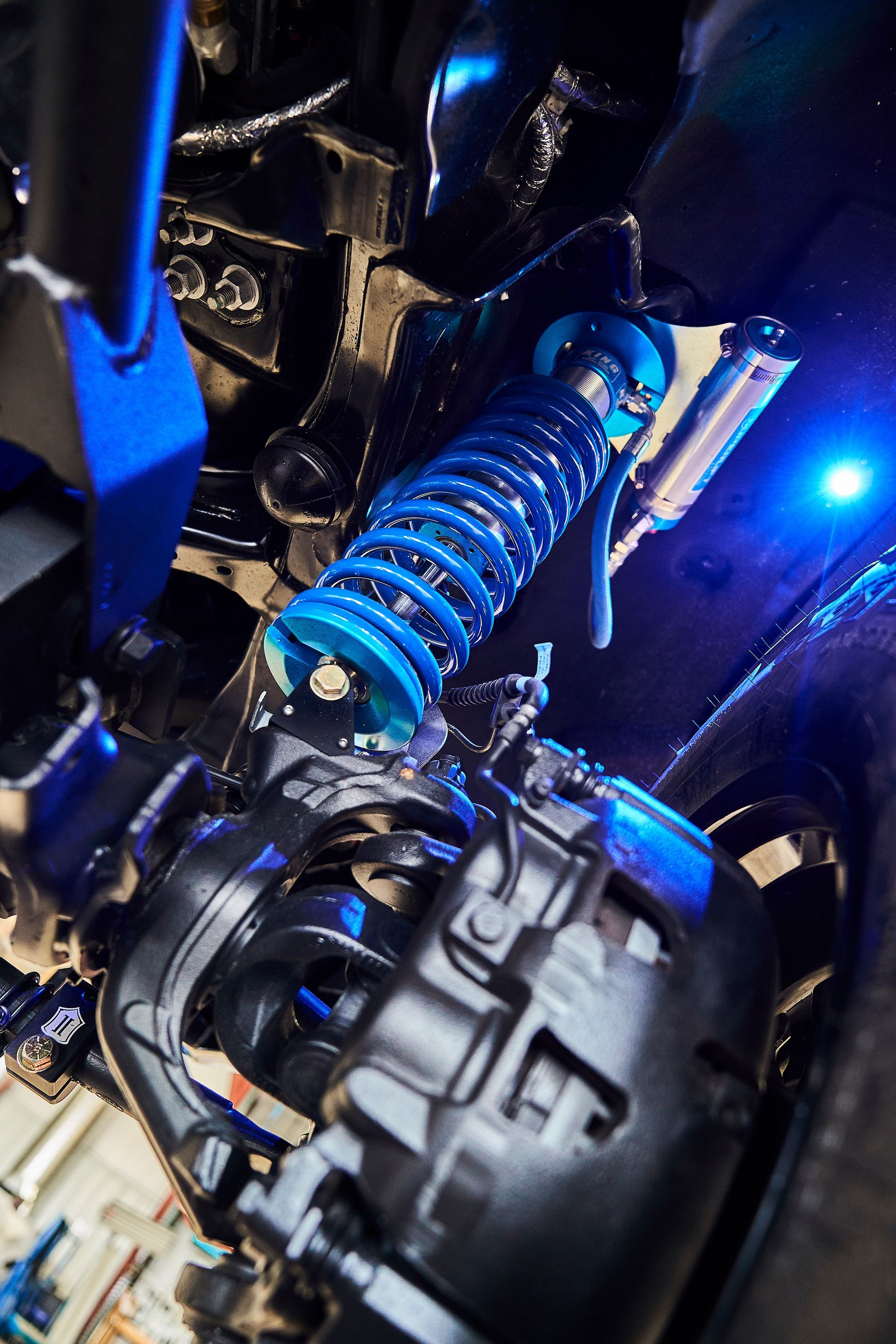 A close up of a shock absorber on a car with blue lights.