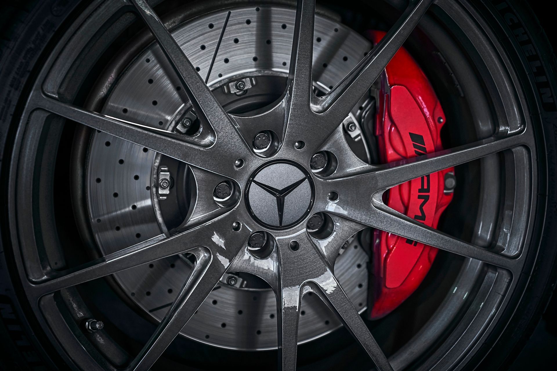 A close up of a mercedes wheel with a red brake caliper