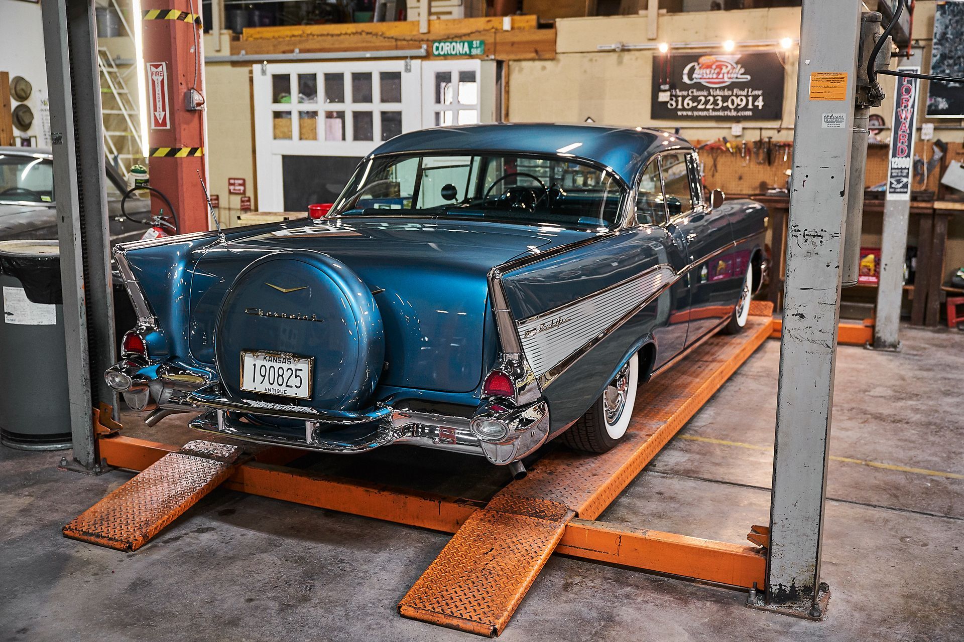 A blue car is sitting on a lift in a garage.