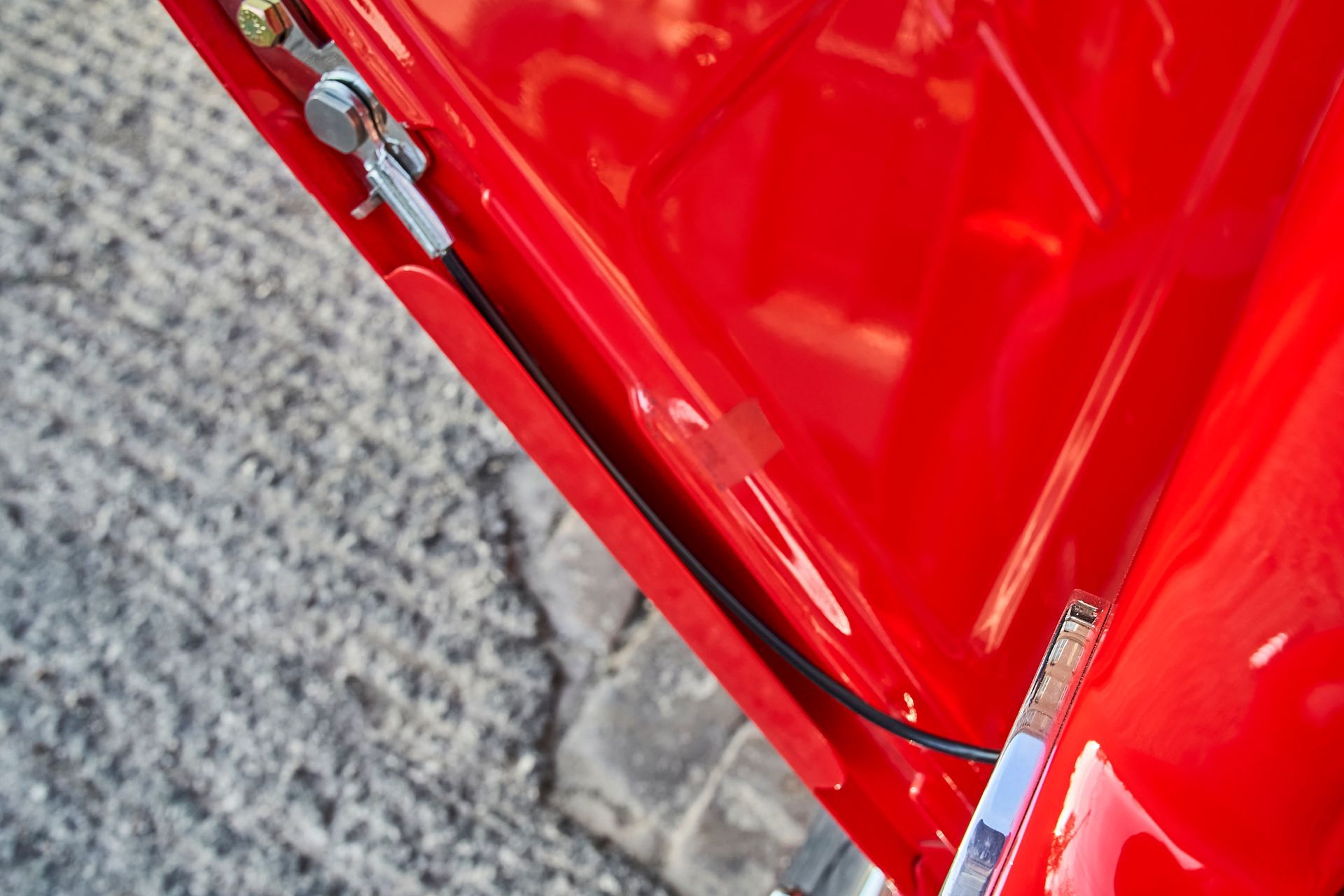 A close up of a red car with a black wire coming out of it
