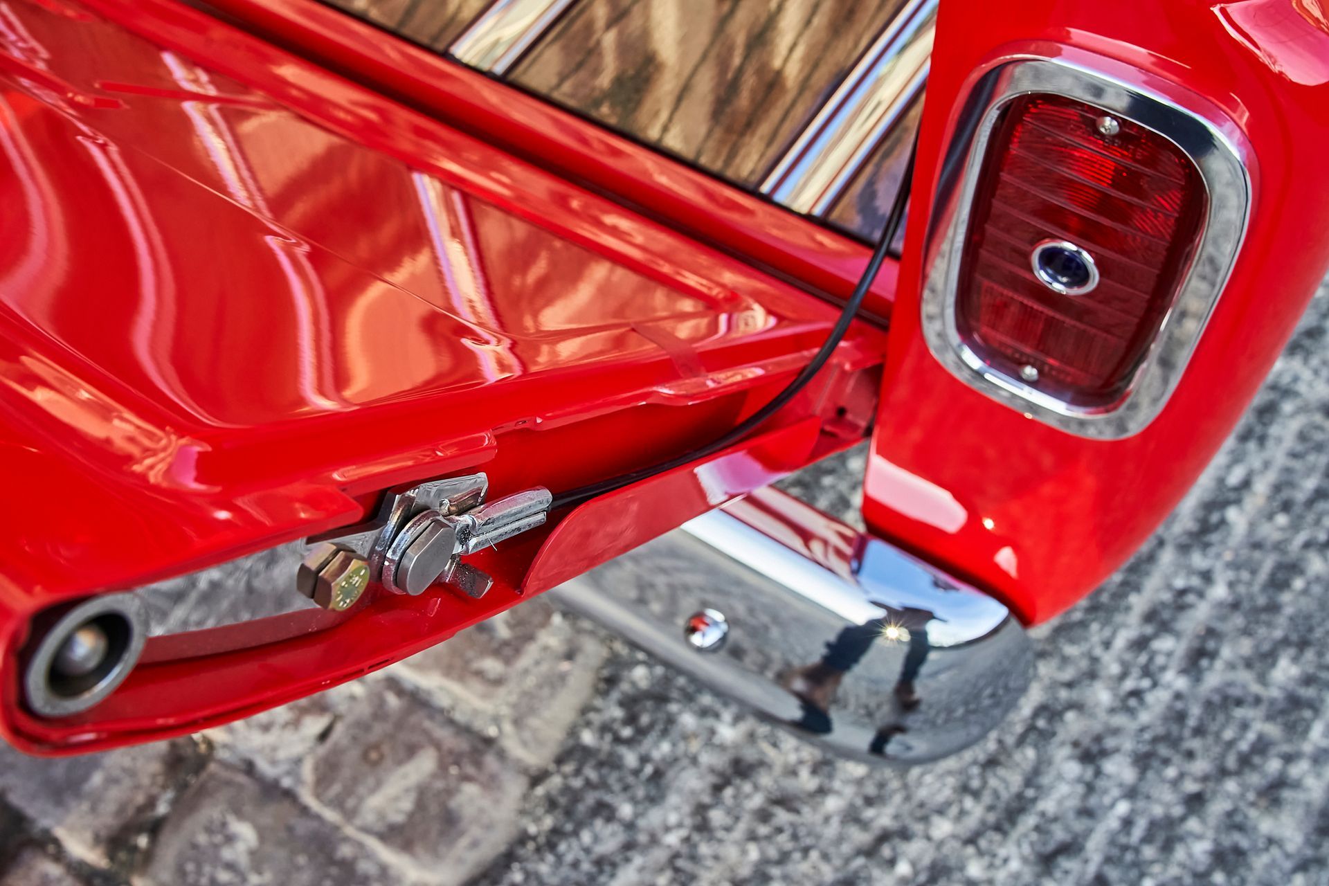A red truck with a wooden bed is parked on the side of the road.