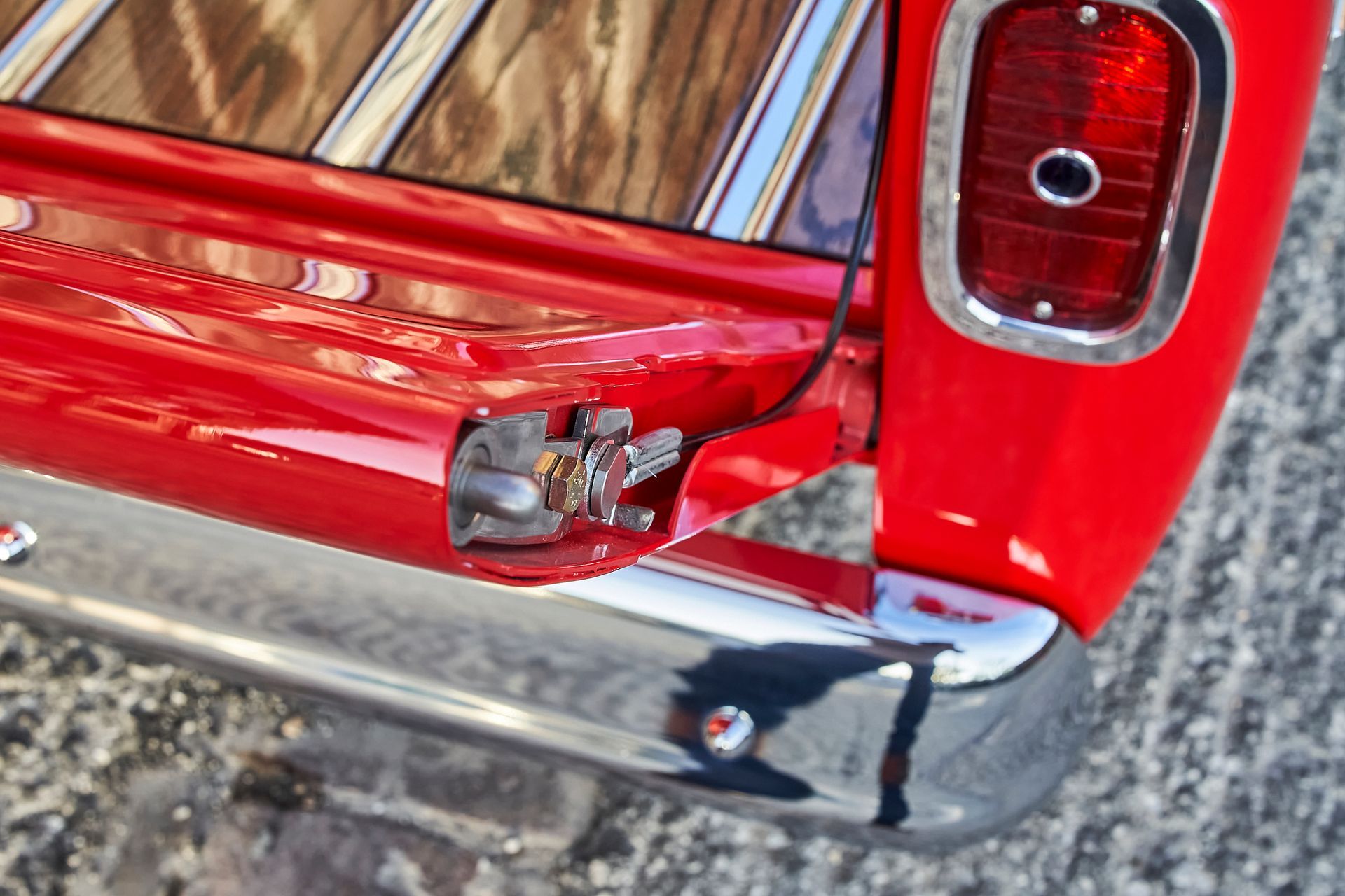 A red truck with a wooden bed and chrome bumper